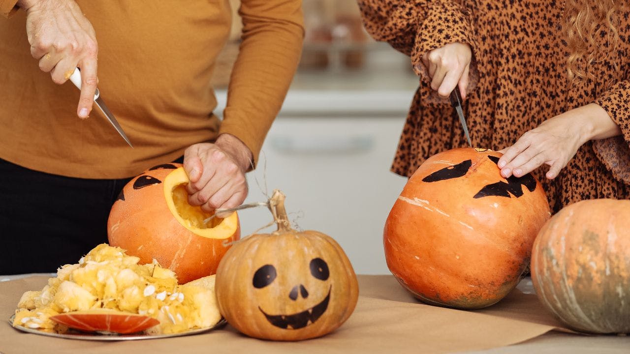 En mand og en kvinde skærer græskar til halloween