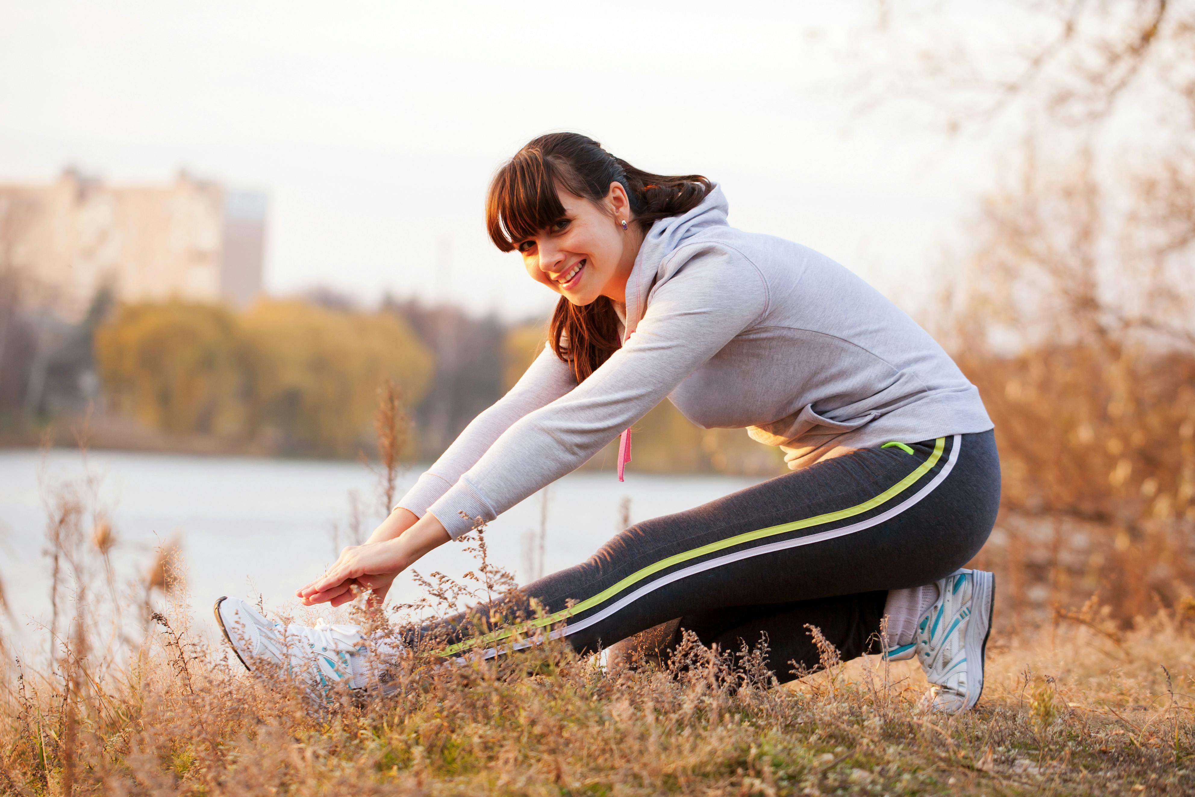 Ung kvinde strækker ud efter motion i naturen