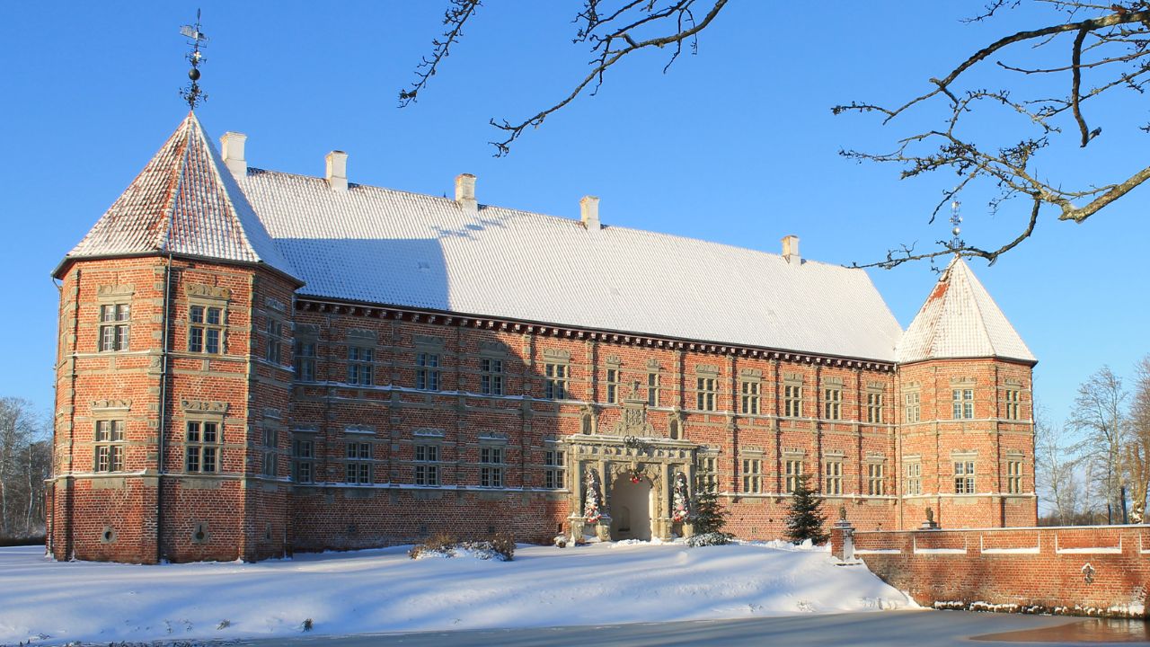 Voergaard Slot i snelandskab med blå himmel