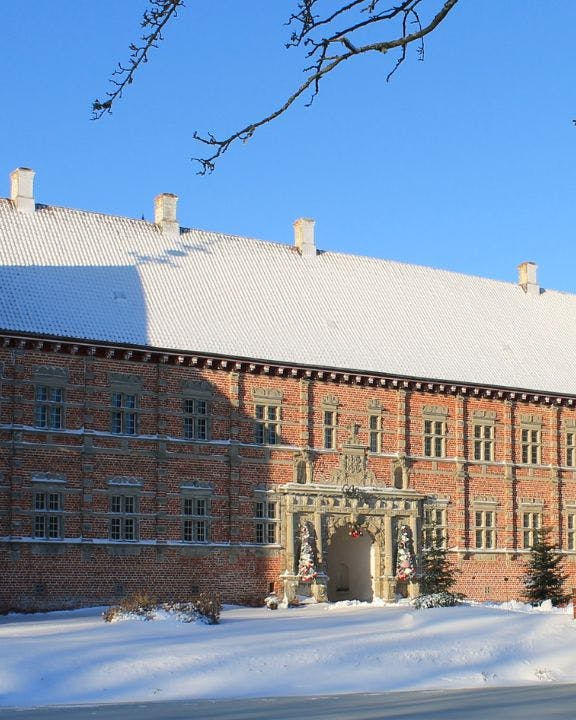 Voergaard Slot i snelandskab med blå himmel