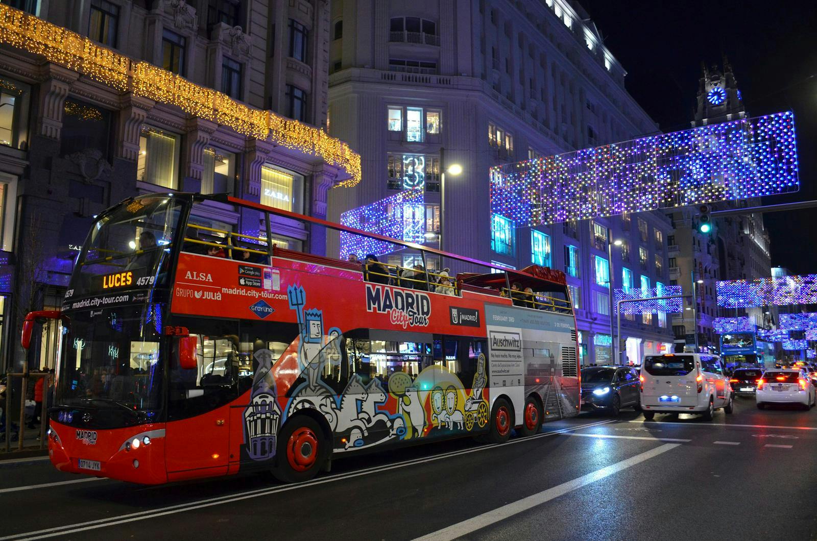 En rød bus, der kører igennem em by med julelys.