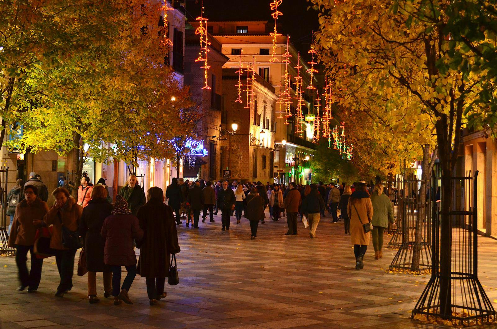 En mørk gade med julelys, hvor folk går op og ned. 