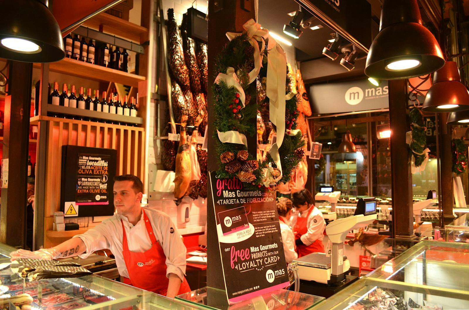 En mand med rødt forklæde, der står i en bod og deler smagsprøver ud. 