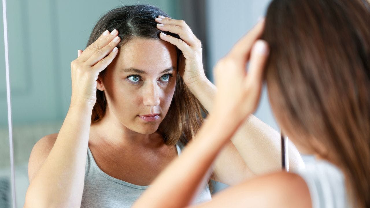 Kvinde kigger sig i spejlet og bekymrer sig om hårtab