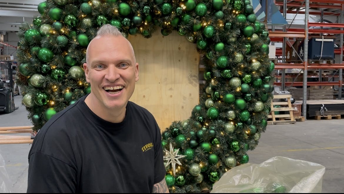 Michael Engel er scenograf i Tivoli og sidder foran en julekrans med julekugler.