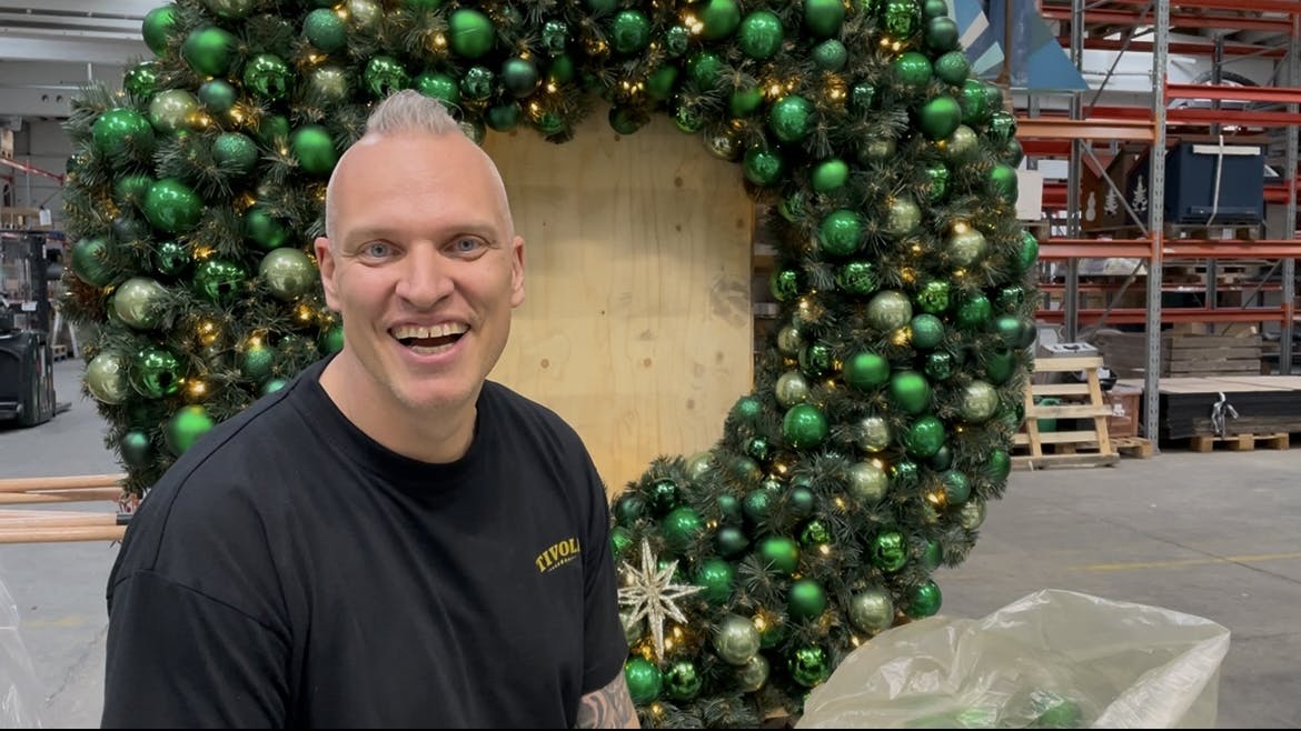 Michael Engel er scenograf i Tivoli og sidder foran en julekrans med julekugler.