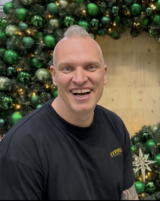 Michael Engel er scenograf i Tivoli og sidder foran en julekrans med julekugler.