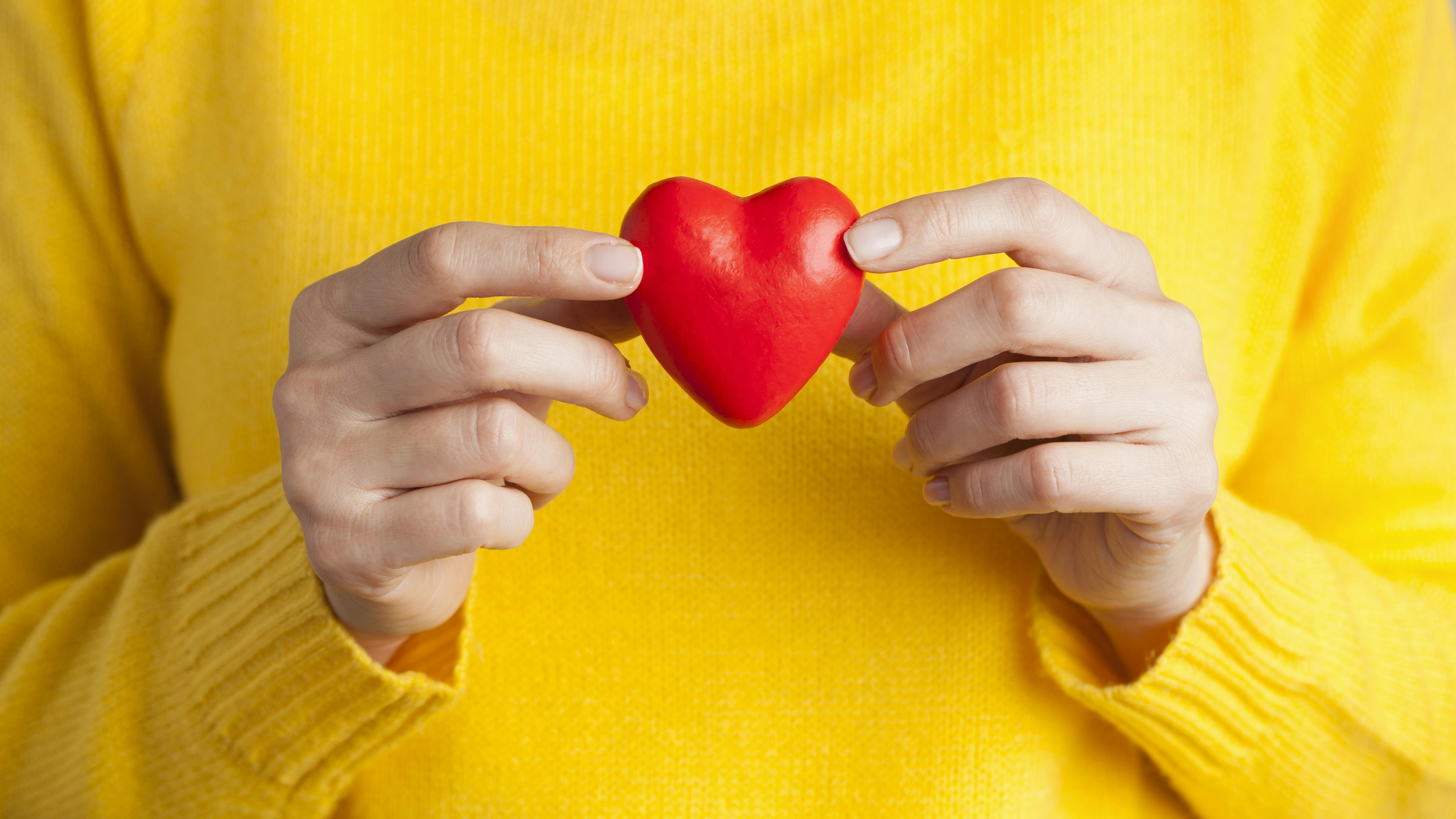 Kvinde, der holder et hjerte mellem hænderne