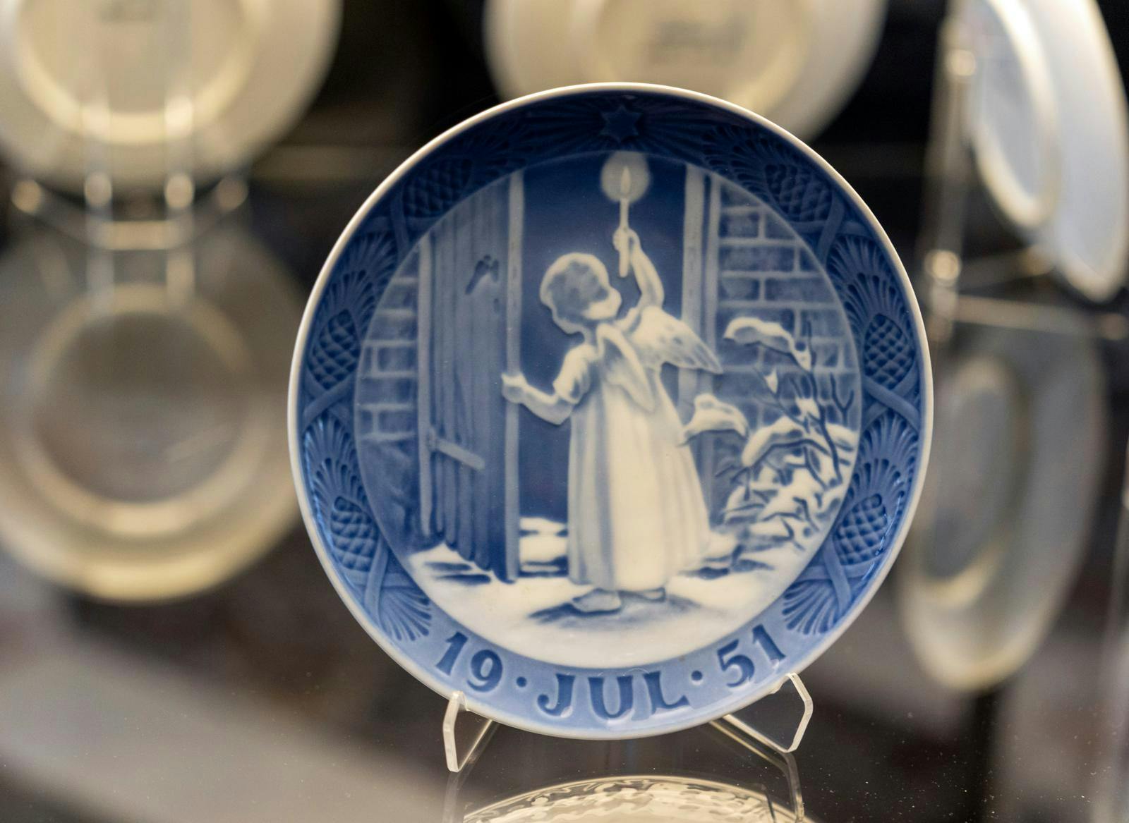 Juleplatte med engel, der er på vej ind ad en dør.