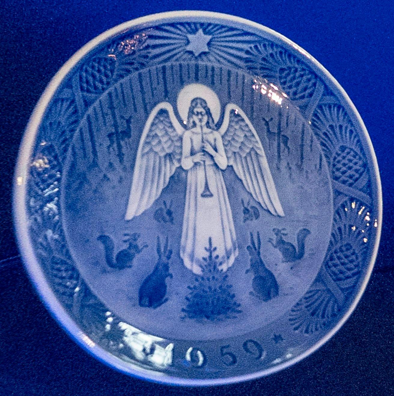 Juleplatte med motiv af en engel, der spiller fløjte for skovens dyr. 