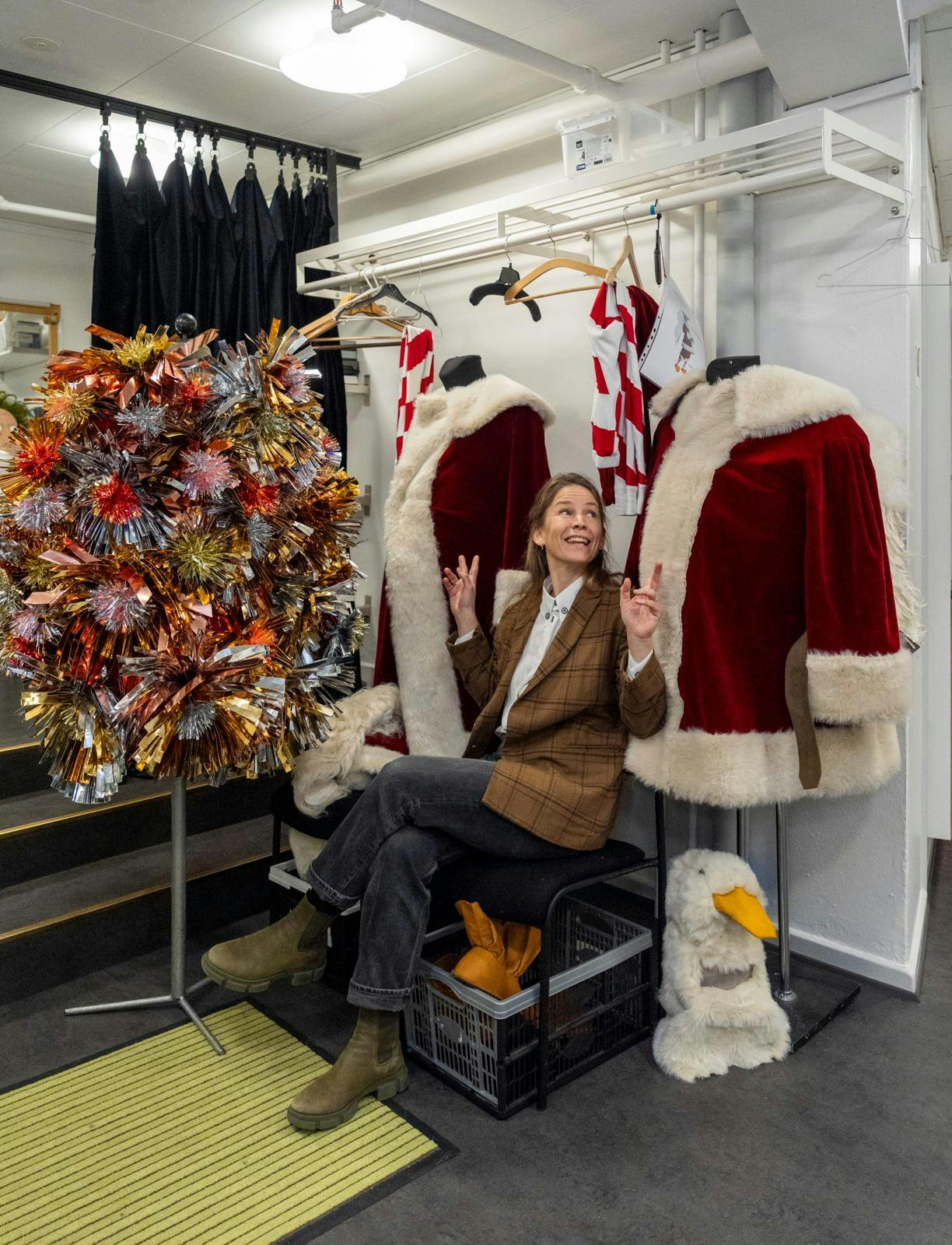 En kvinde, der sidder på en stol mellem to julemandskostumer.