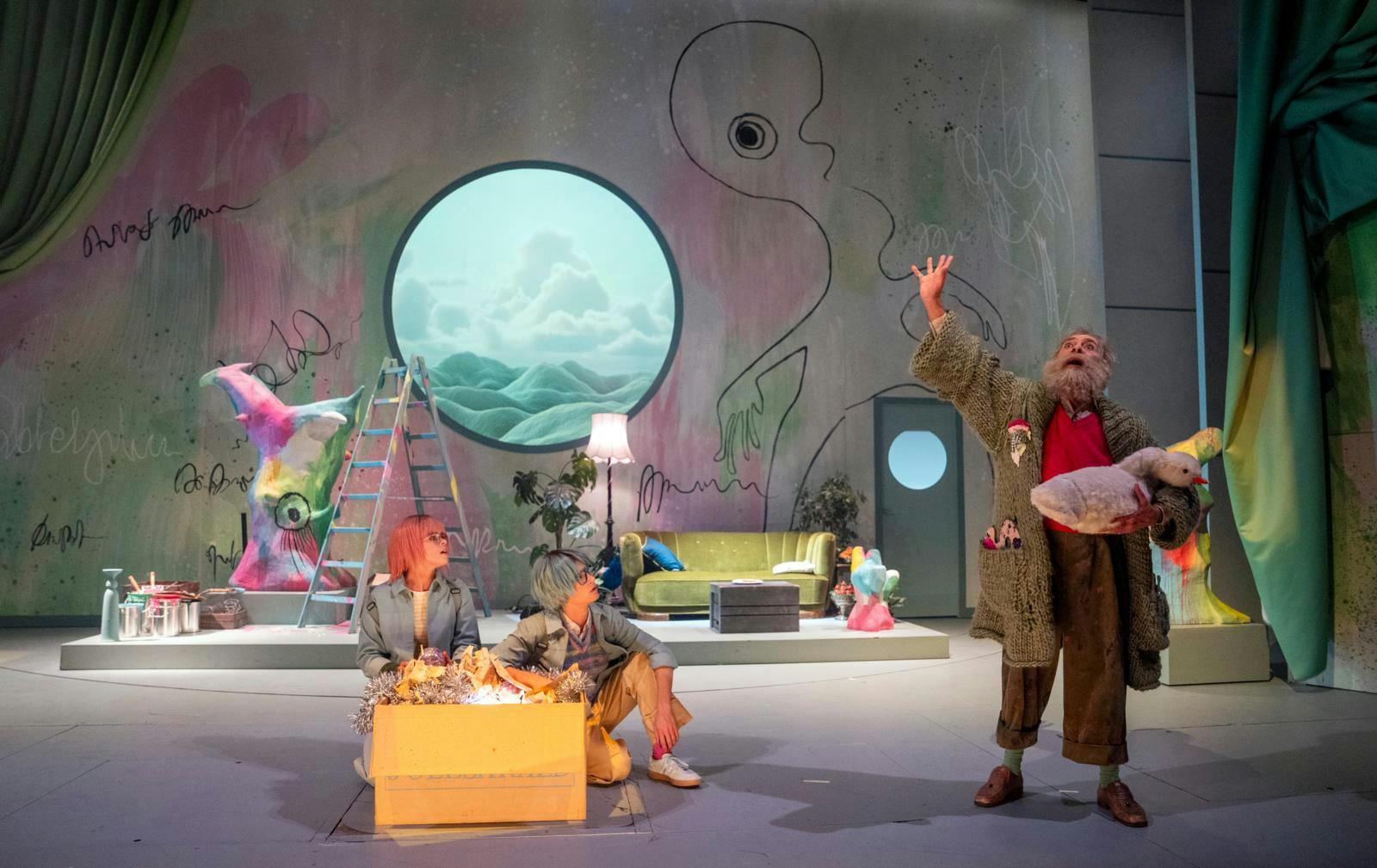 En scene med to børn og en ældre mand samt en masse farverige kulisser.