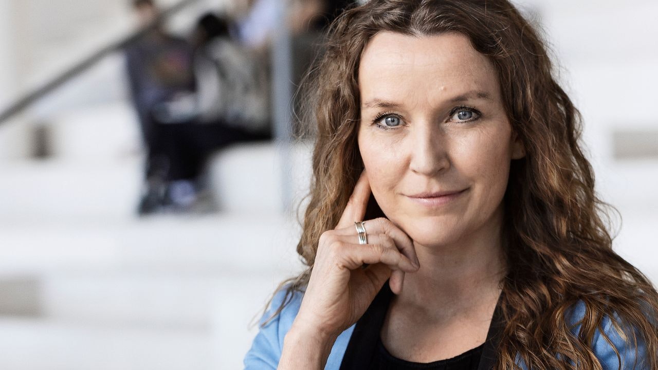 Kvinde står foran hvid trappe og kigger ind i kameraet