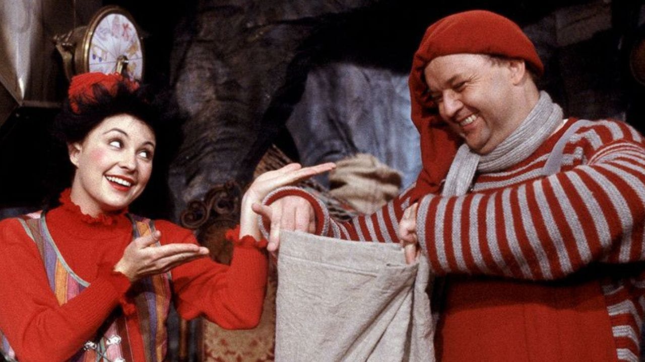 To nisser smiler og står med en sæk med gaver