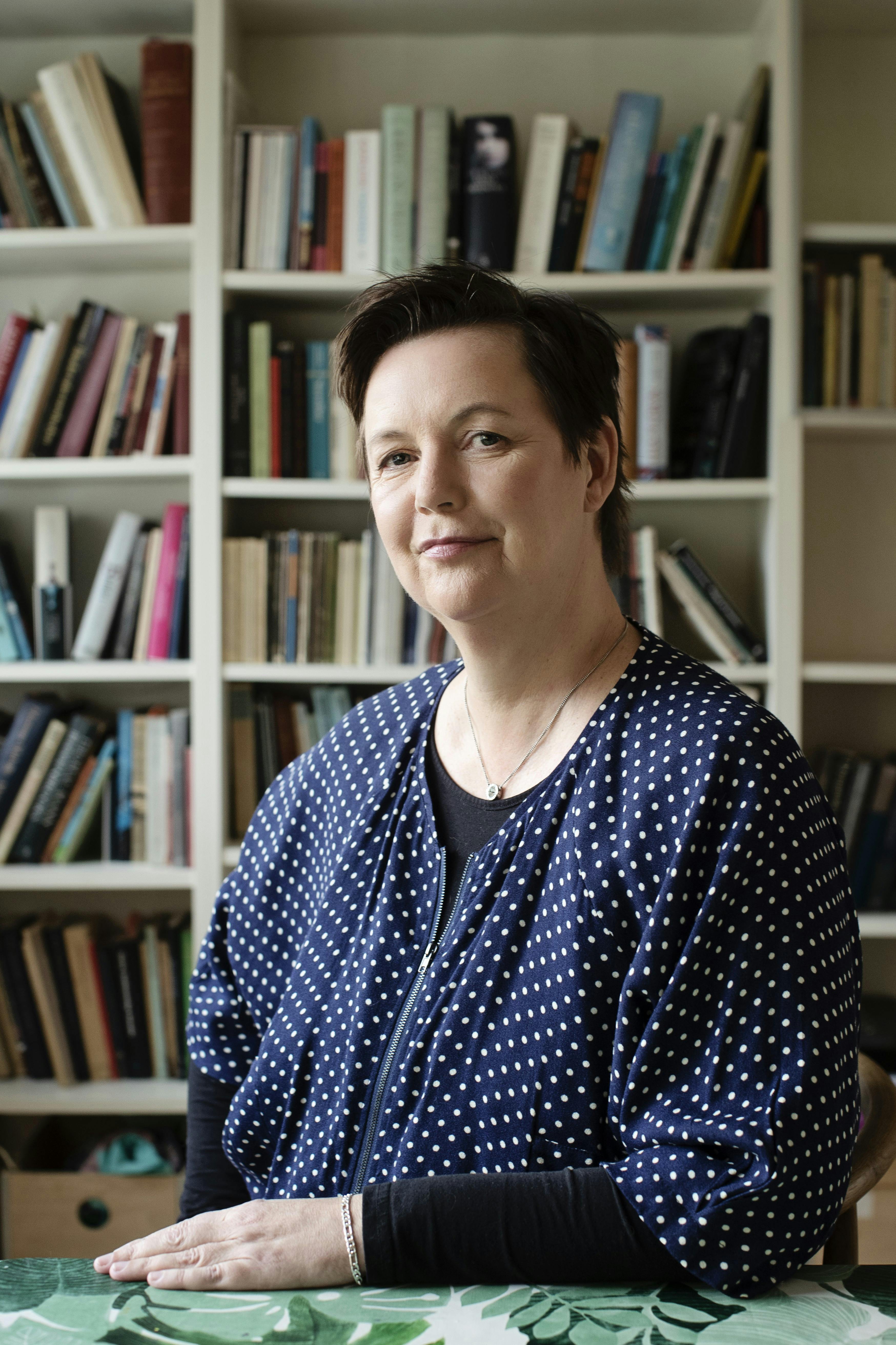 Forfatter Katrine Marie Guldager med bogreol i baggrunden.