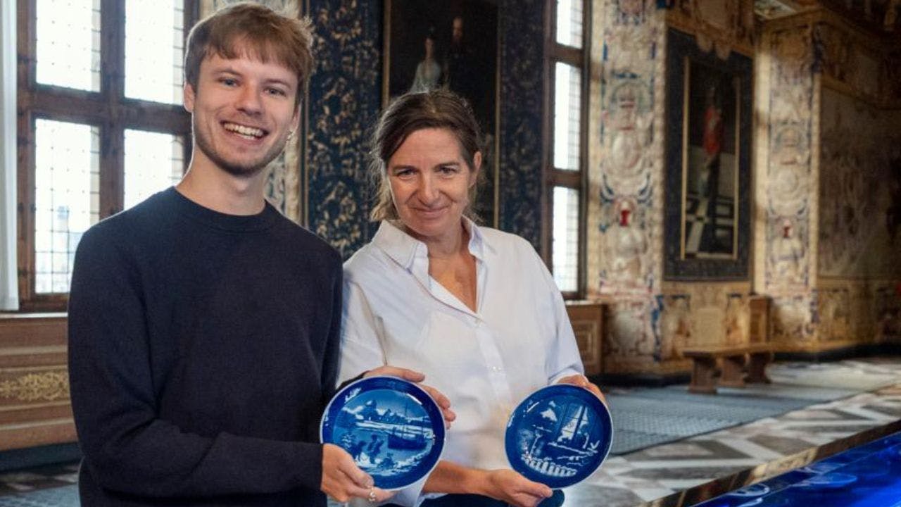 Mand og kvinde står foran et blåt langbord og holder hver sin juleplatte op