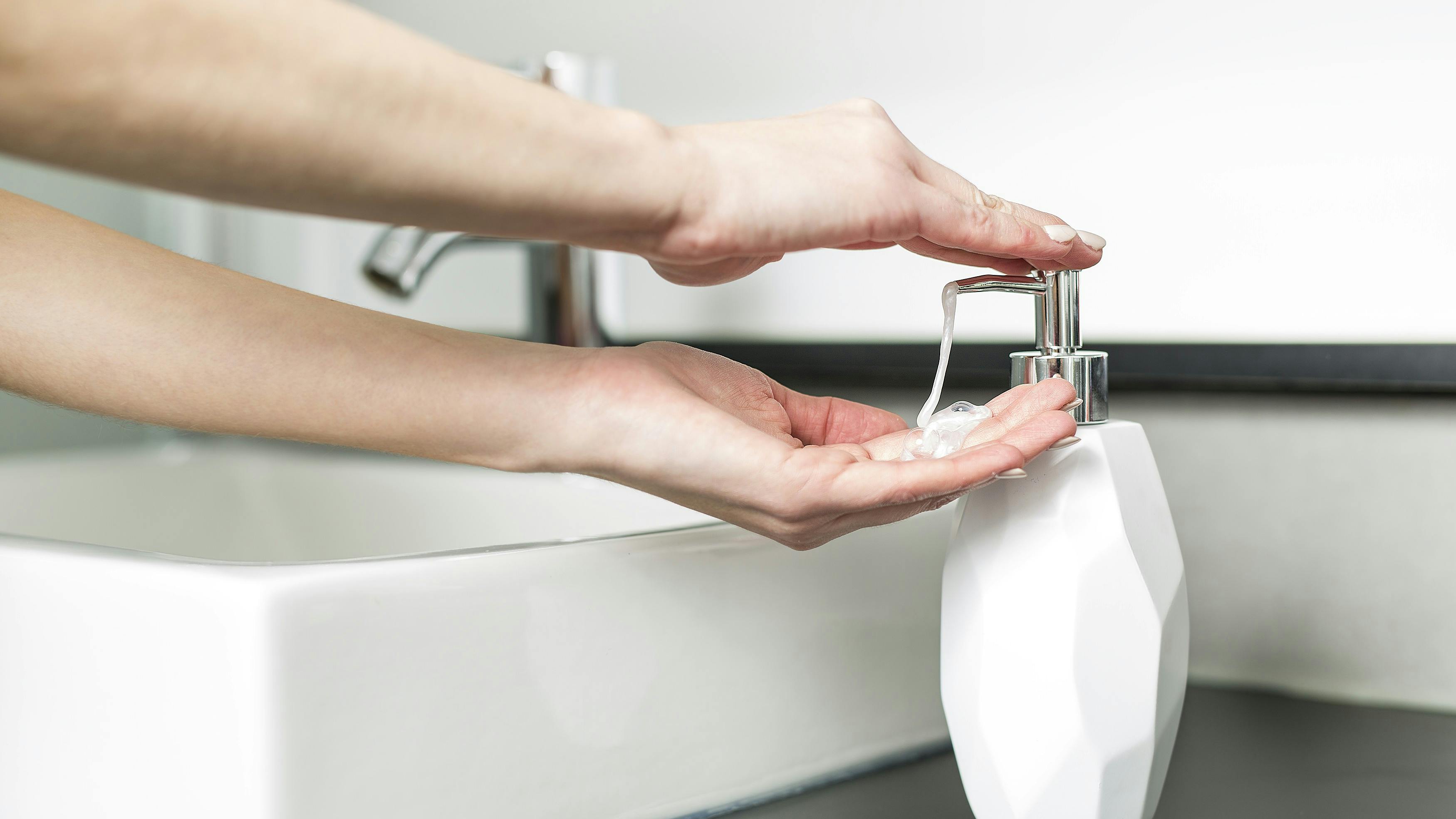 Kvinde tager sæbe fra en dispenser.