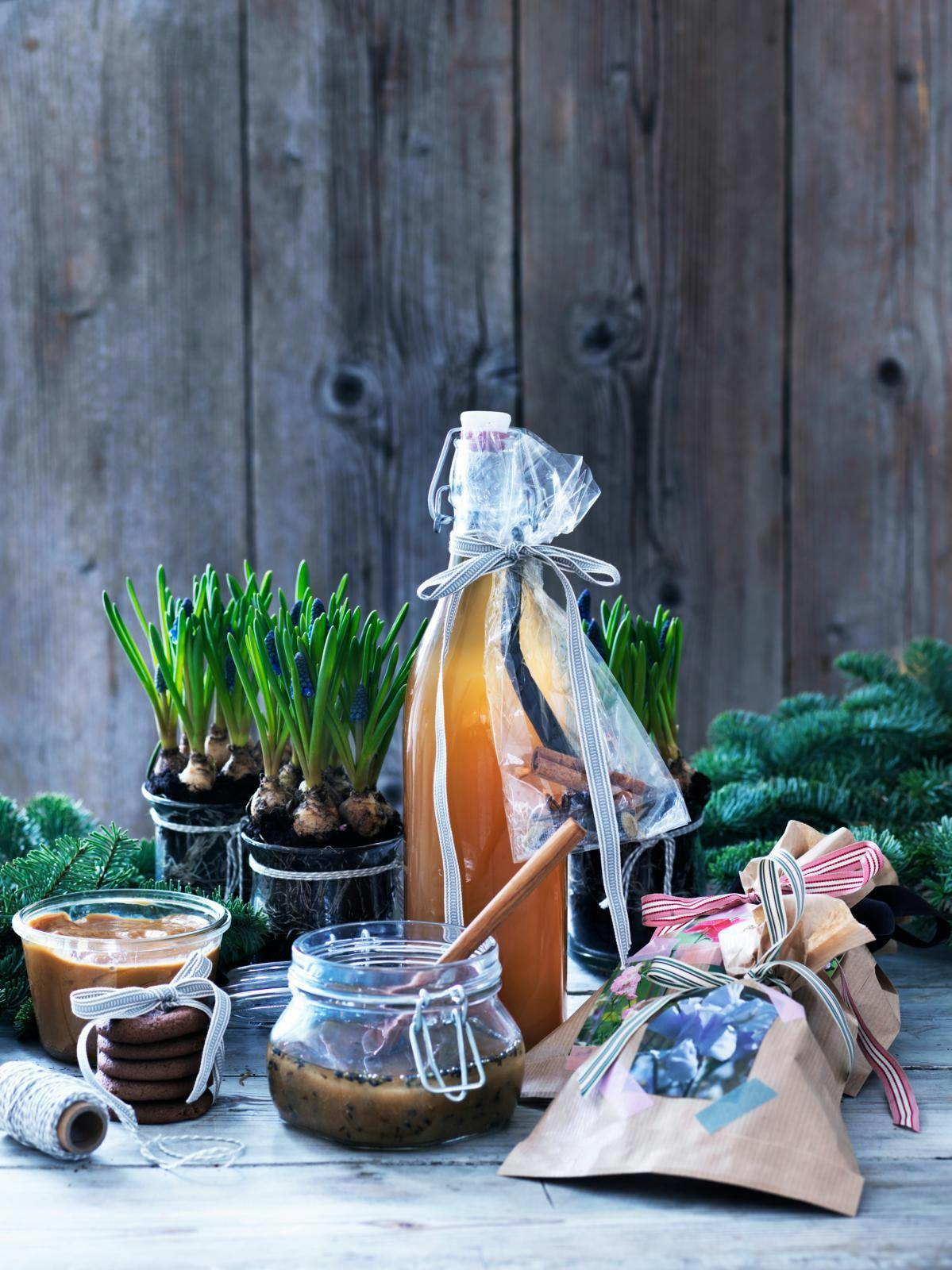 Et bord med hjemmelavede spiselige gaver og krukker med løgplanter