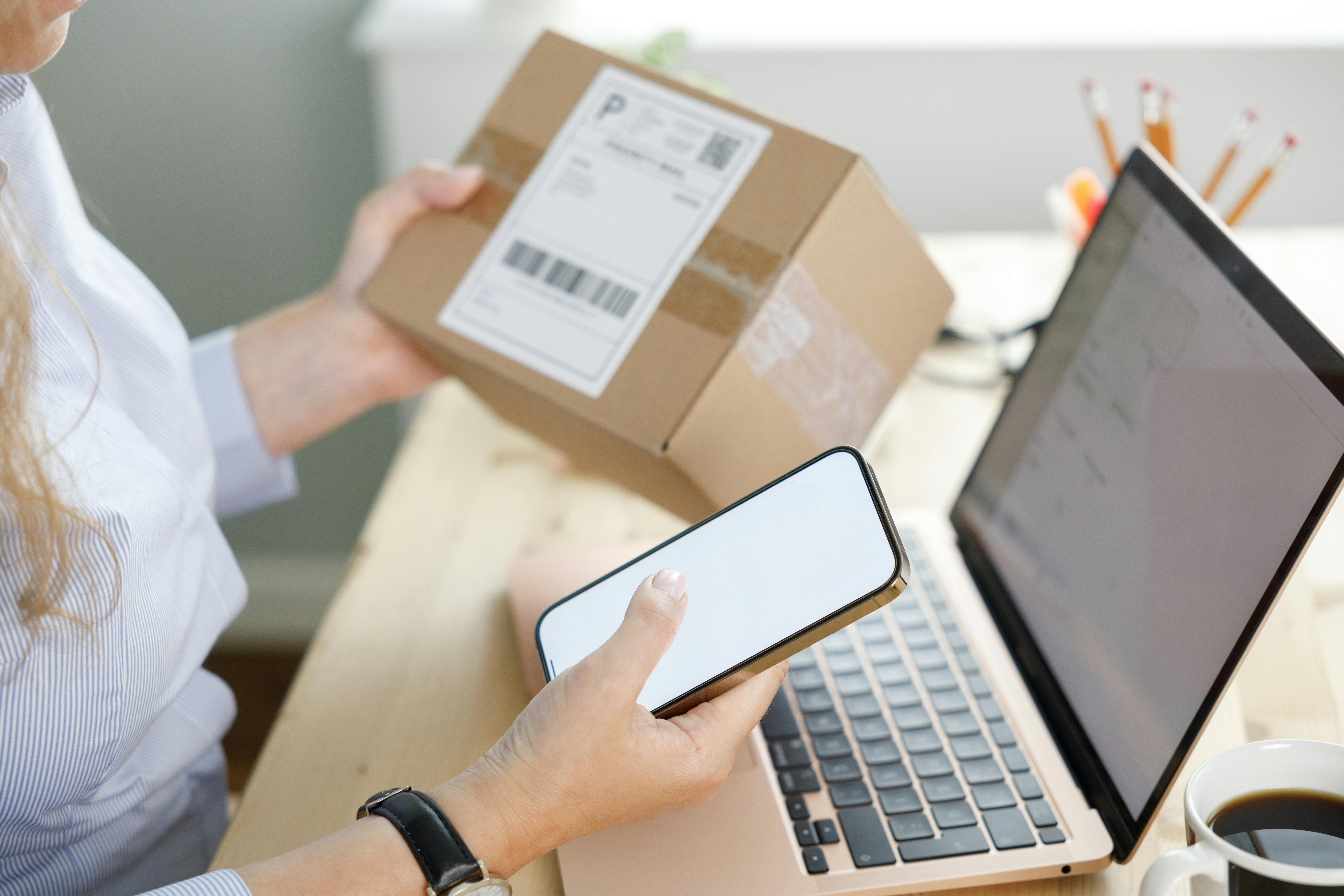 Ung kvinde handler på nettet med sin computer og mobil