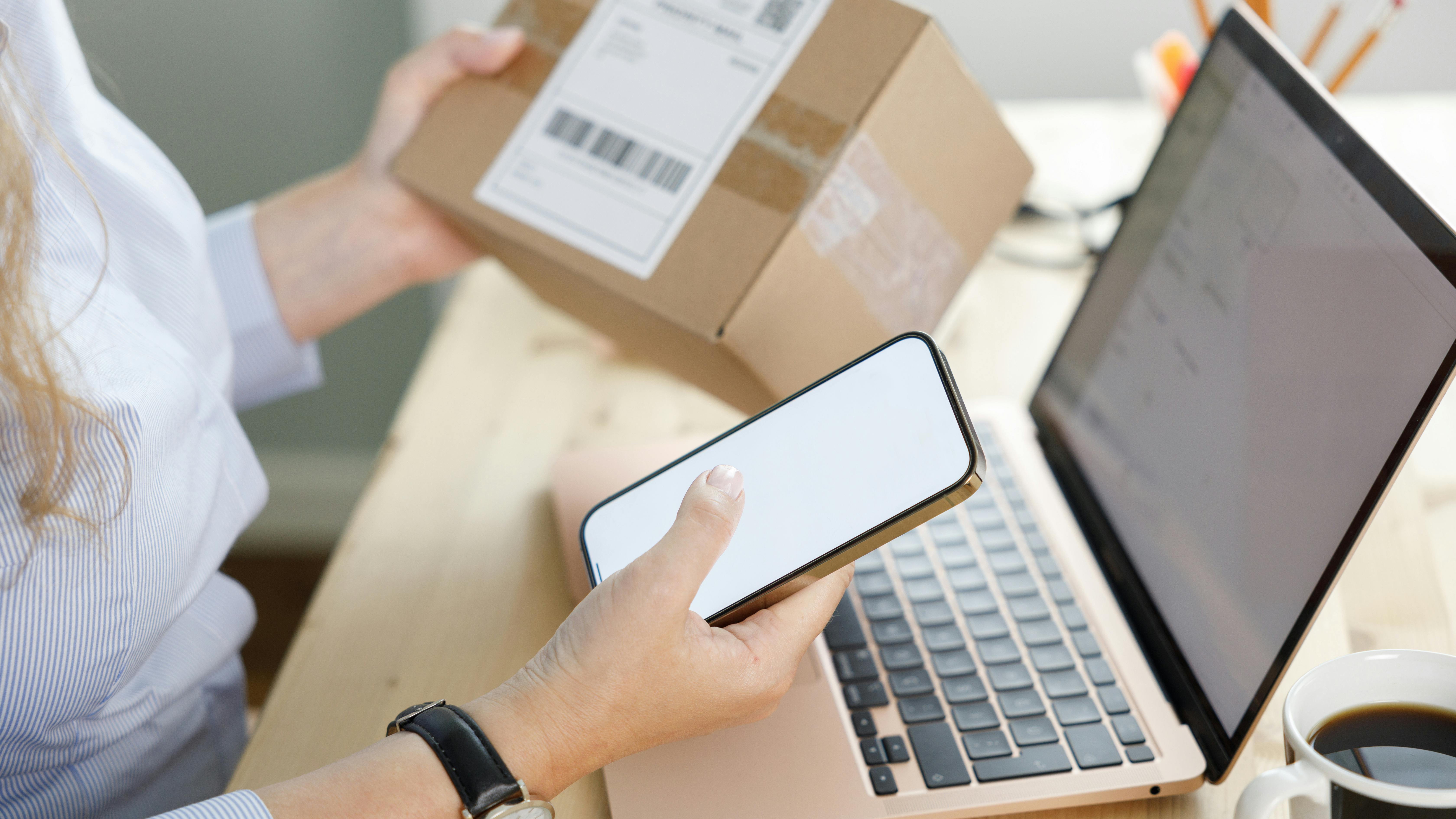 Ung kvinde handler på nettet med sin computer og mobil