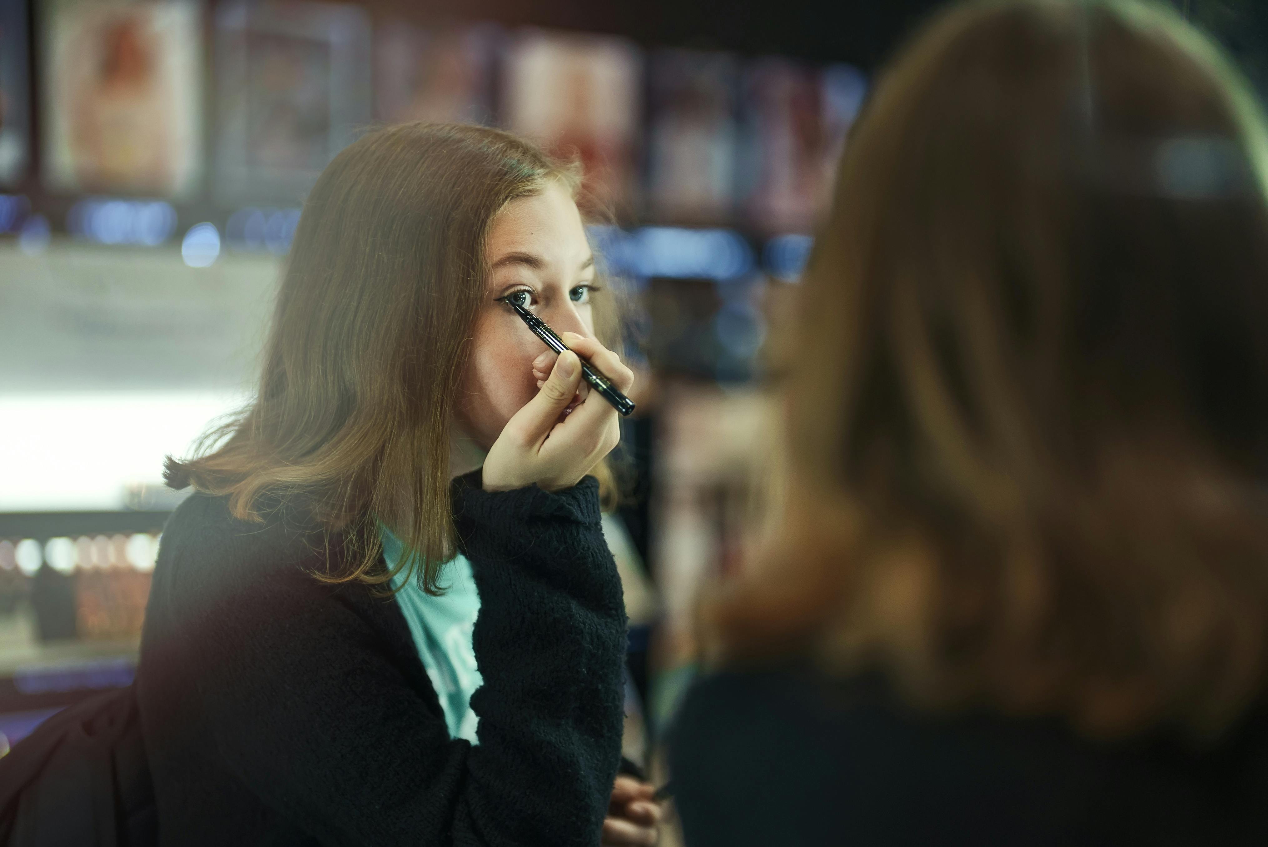 Teenagepige lægger makeup foran et spejl