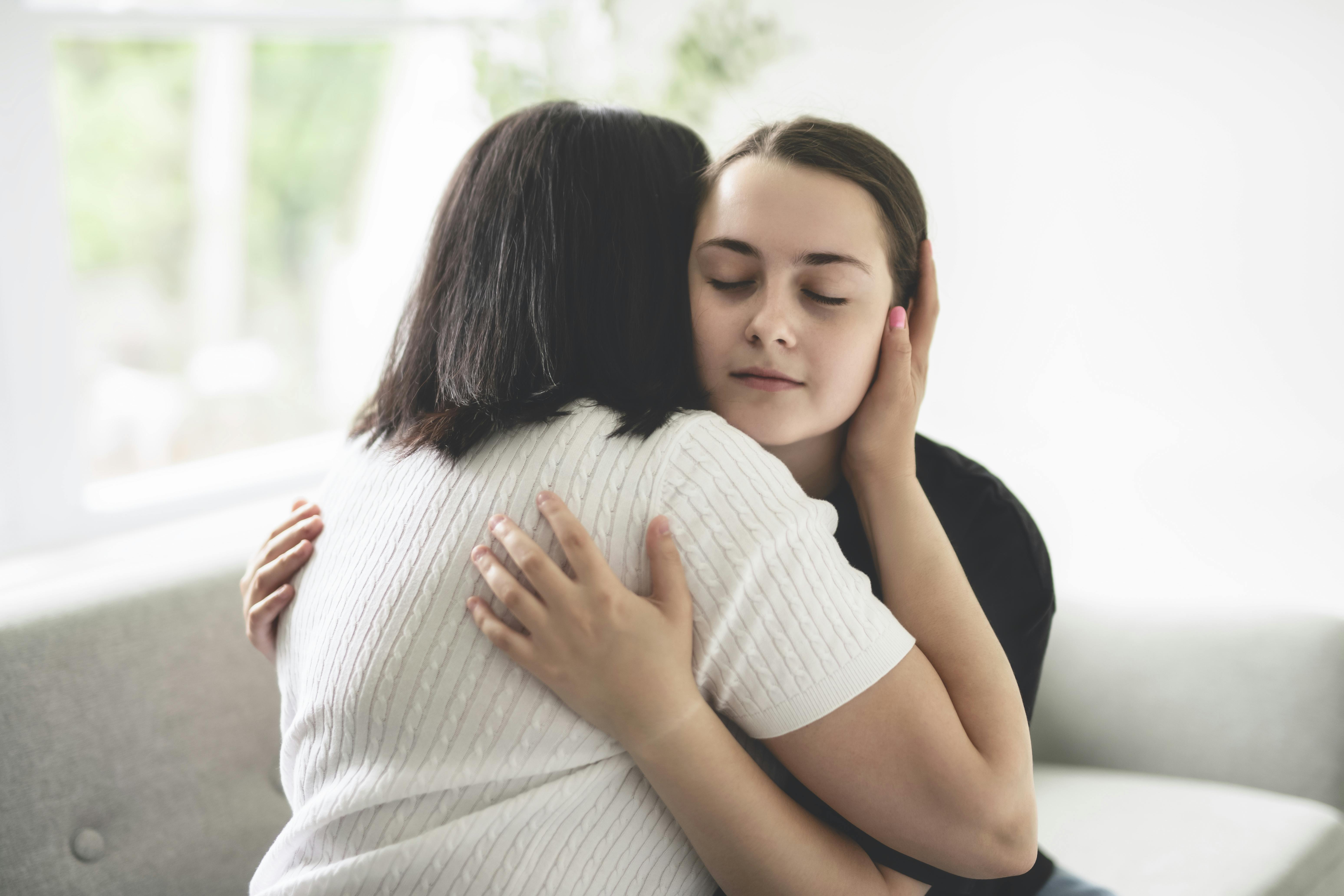 Mor og teenagedatter krammer