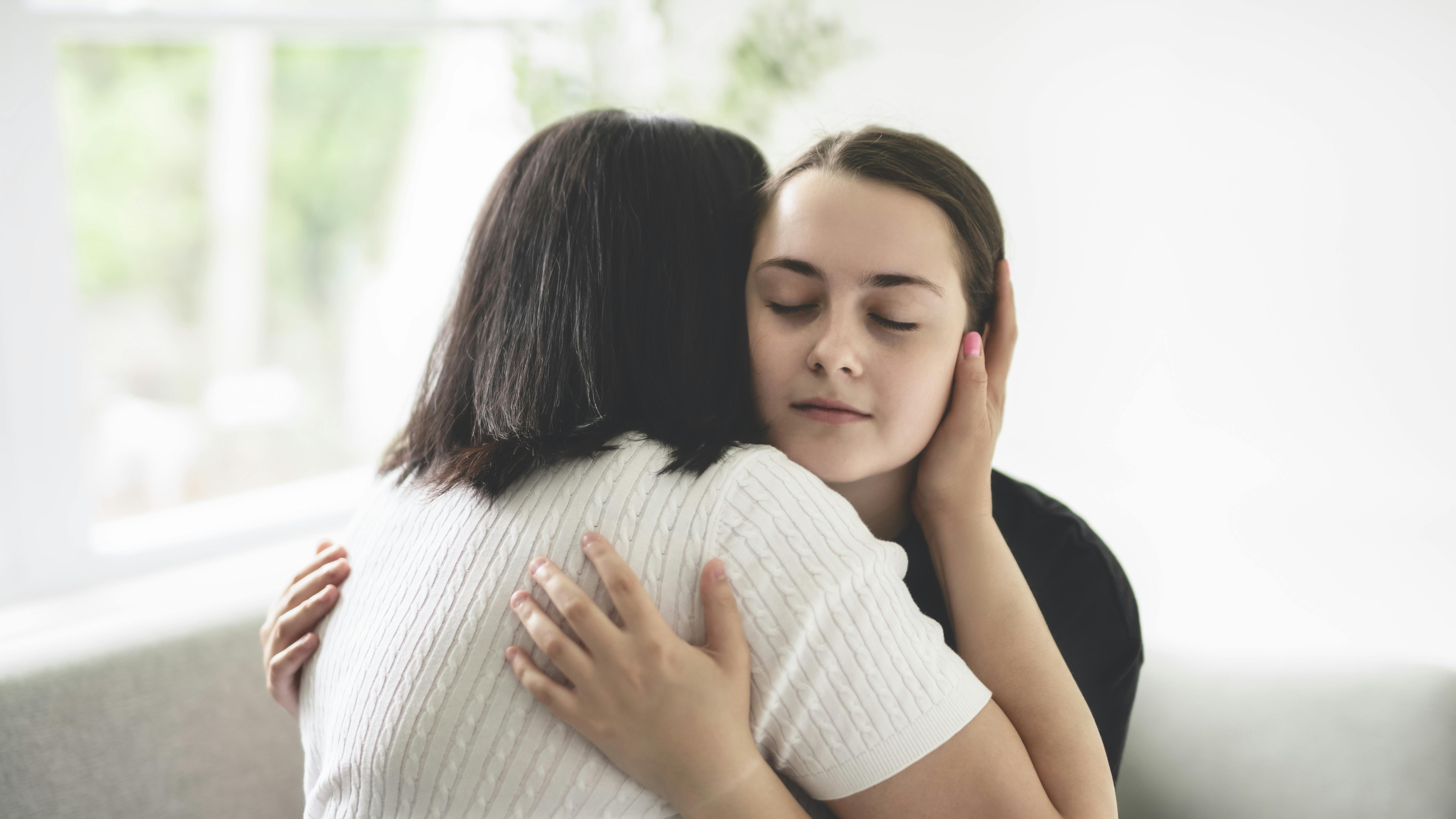 Mor og teenagedatter krammer