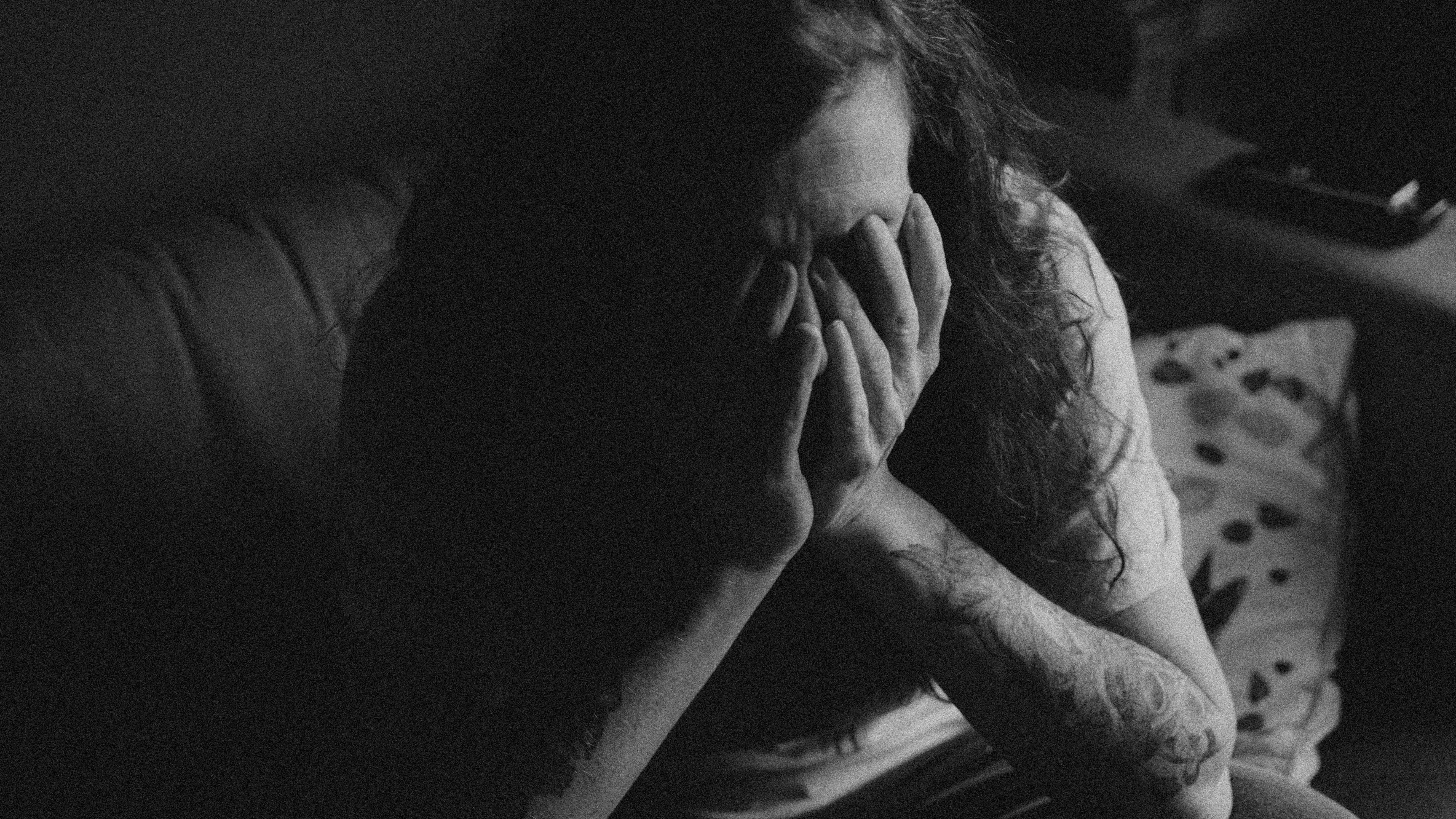 En kvinde, der sidder med bøjet hoved i hænderne.