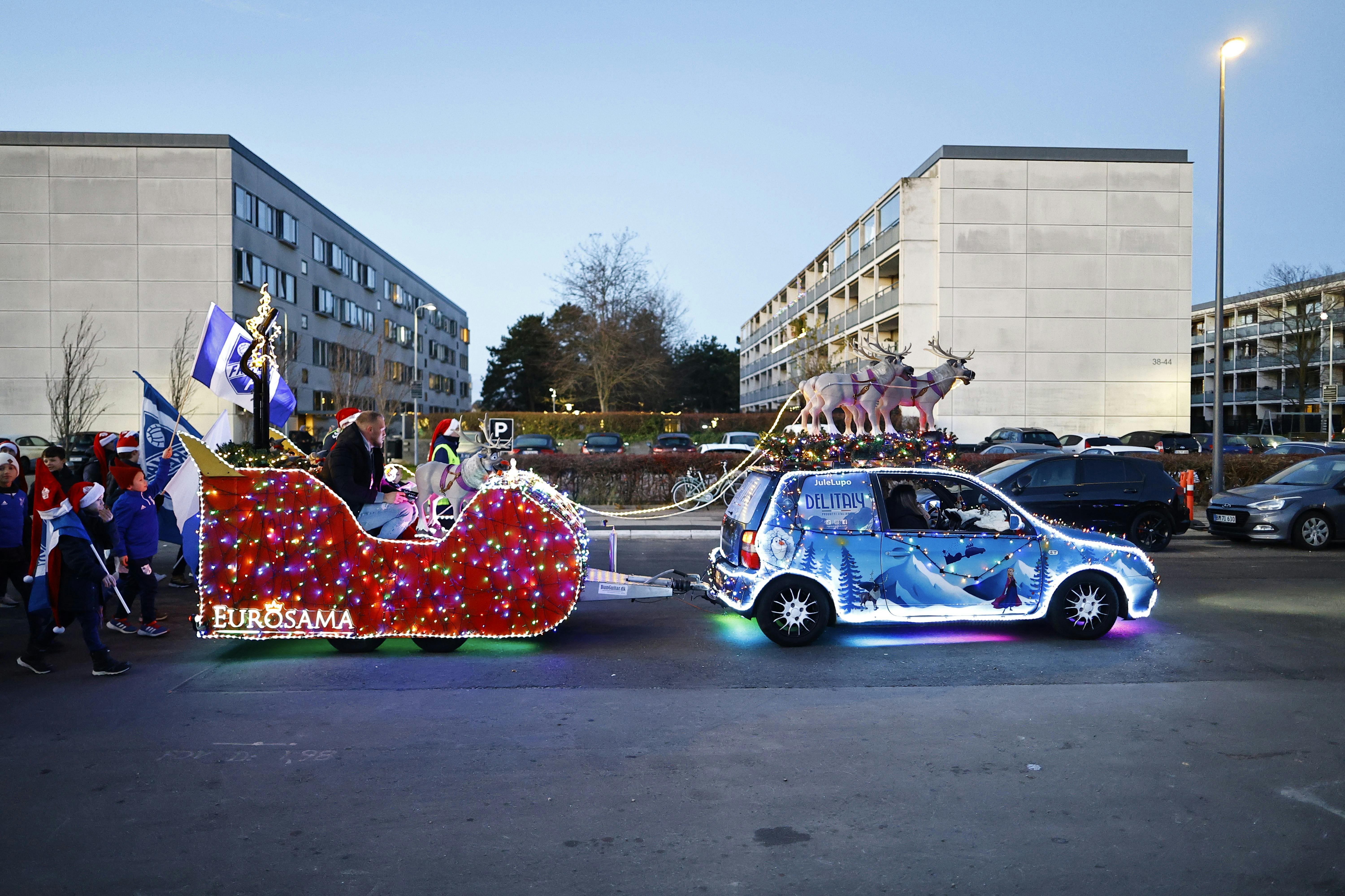 En lysende blå bil holder med en rød lysende julekane bag sig