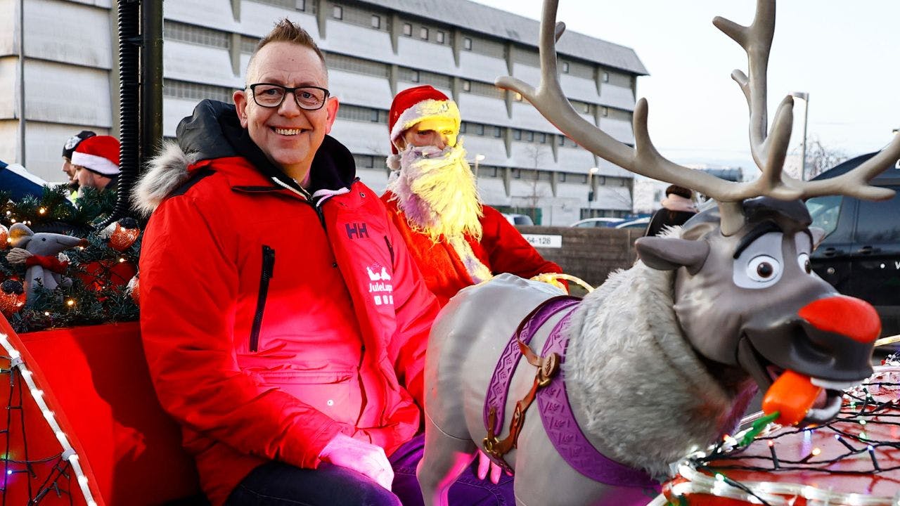 Mand sidder i en rød julekane med et plastik rensdyr med rød tud