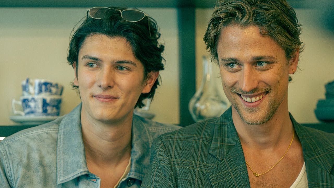 To unge mænd står ved siden af hinanden og smiler