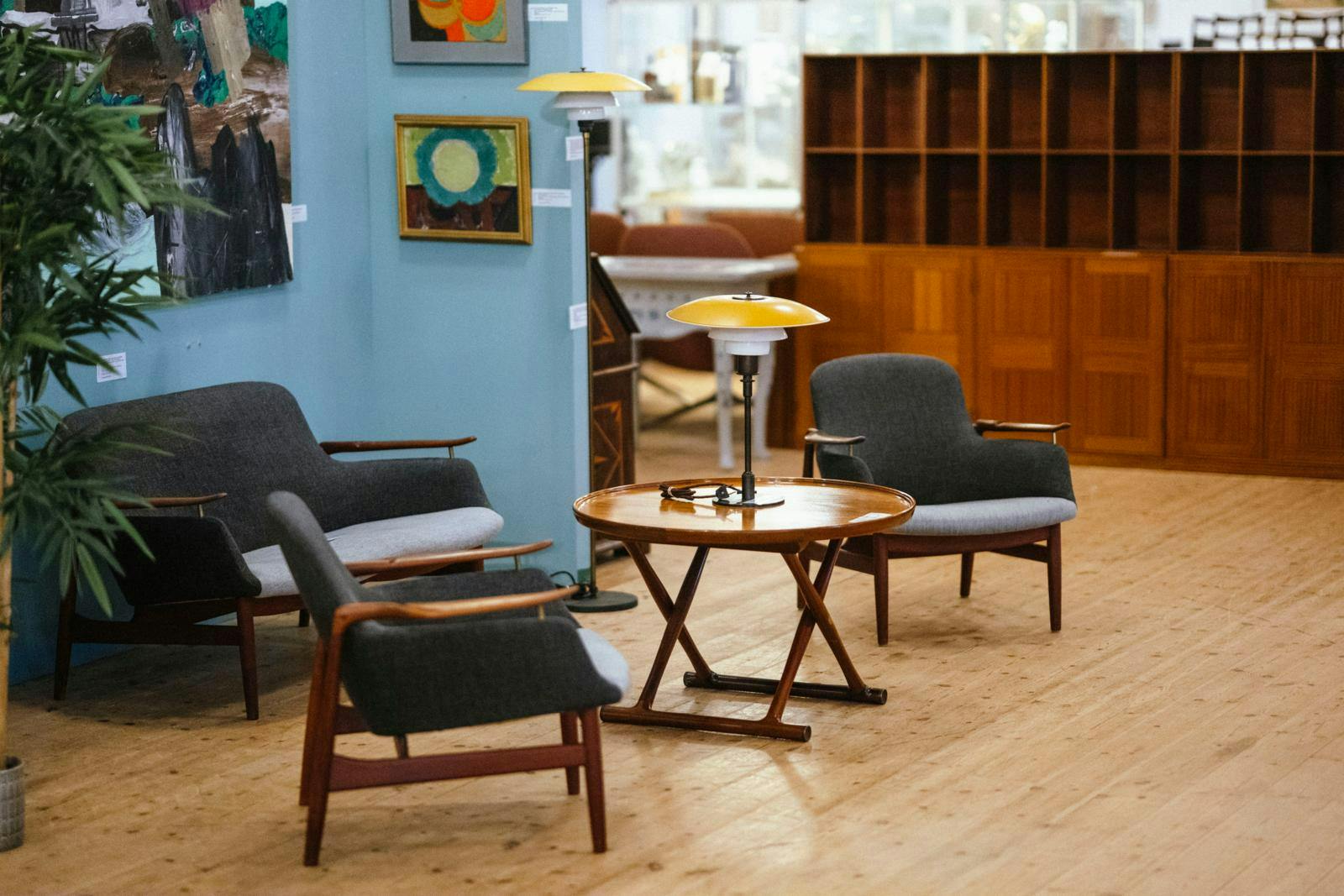 Møbelinteriør med gamle lænestole, sofabord, lamper og en reol