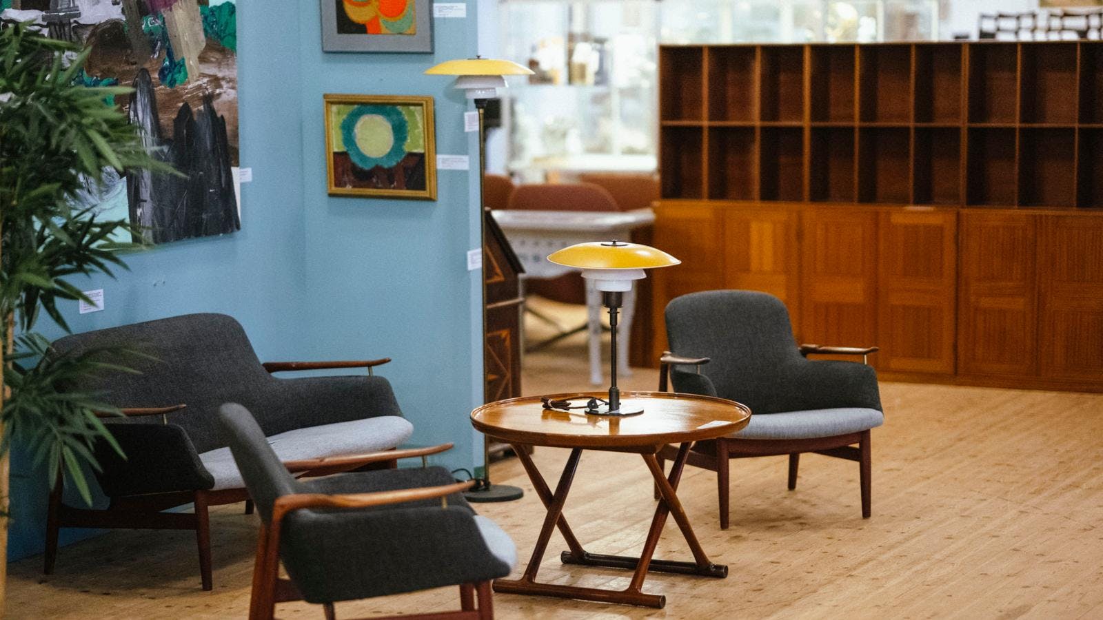 Møbelinteriør med gamle lænestole, sofabord, lamper og en reol