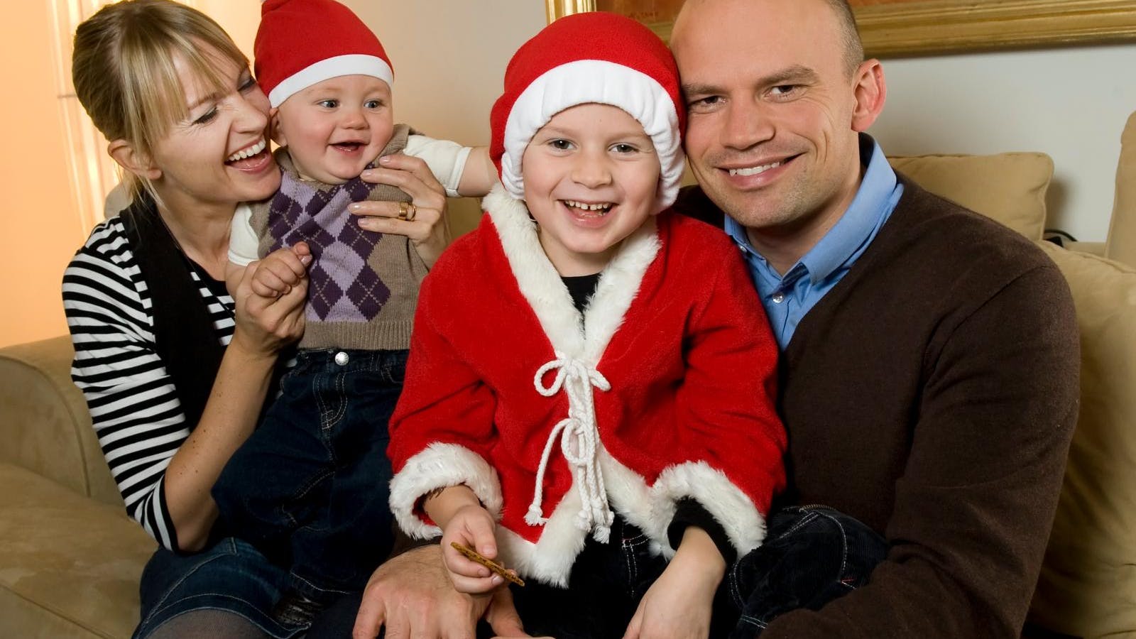 Jesper Vollmer og Annette Heick i en sofa med deres to børn, der har nissetøj og nissehuer på