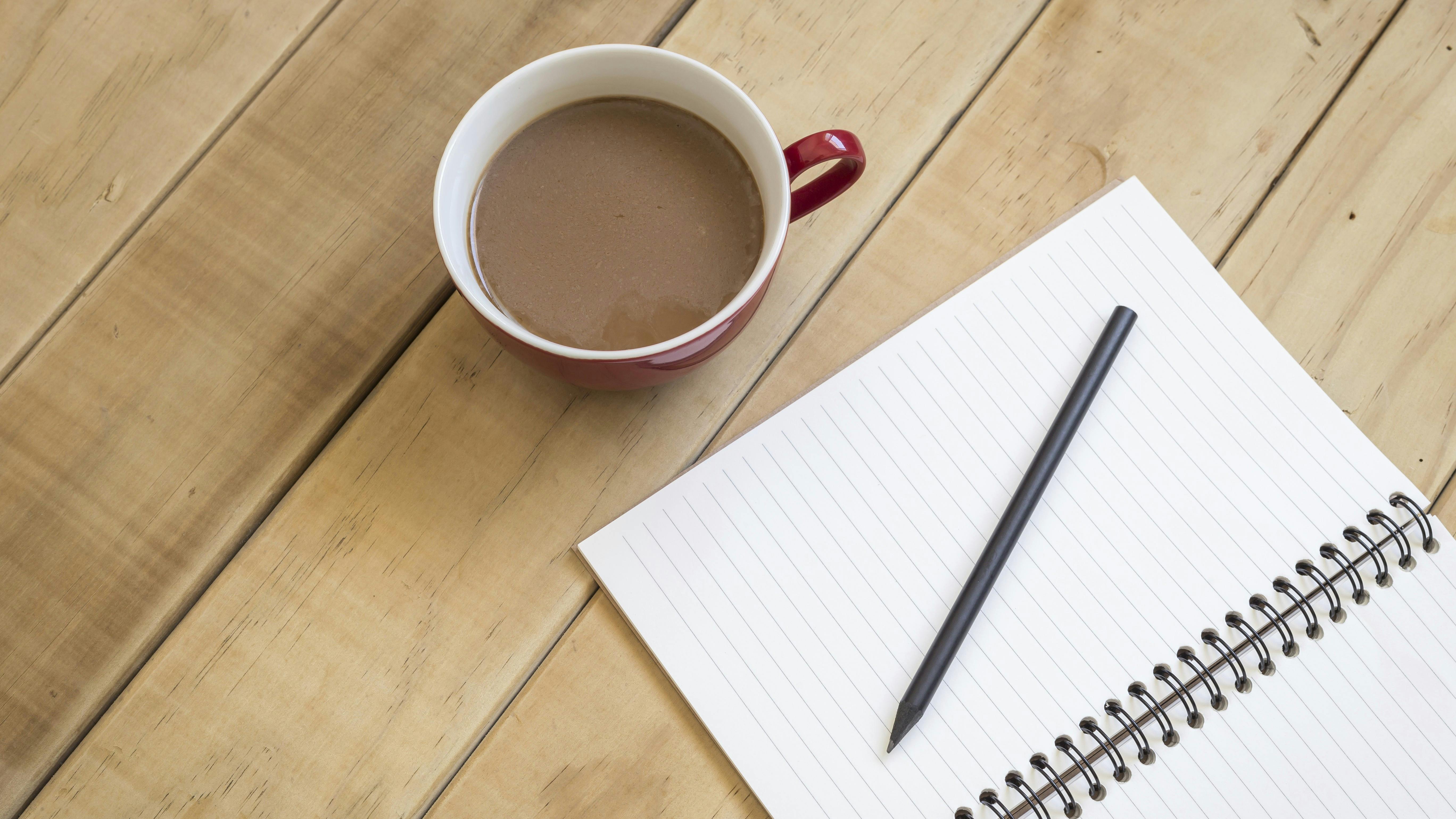 Foto af kop kaffe og notesbog.