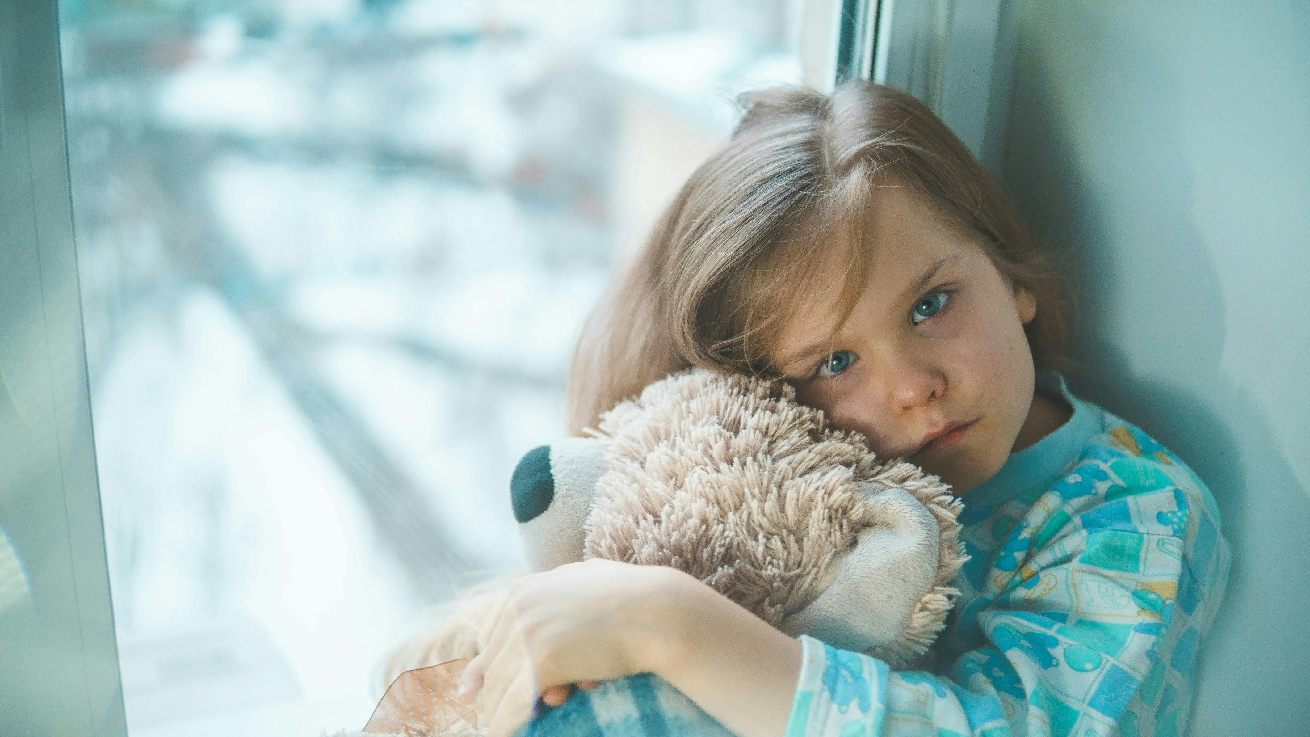 En pige, der sidder og knuger en bamse