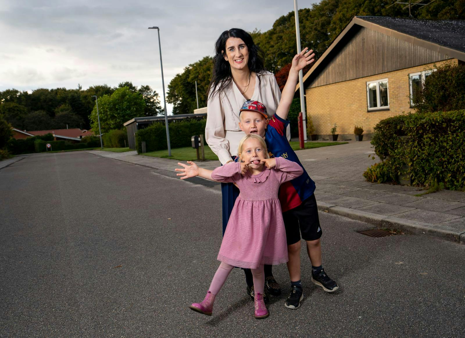 En vej, hvor der står en mor med to børn.