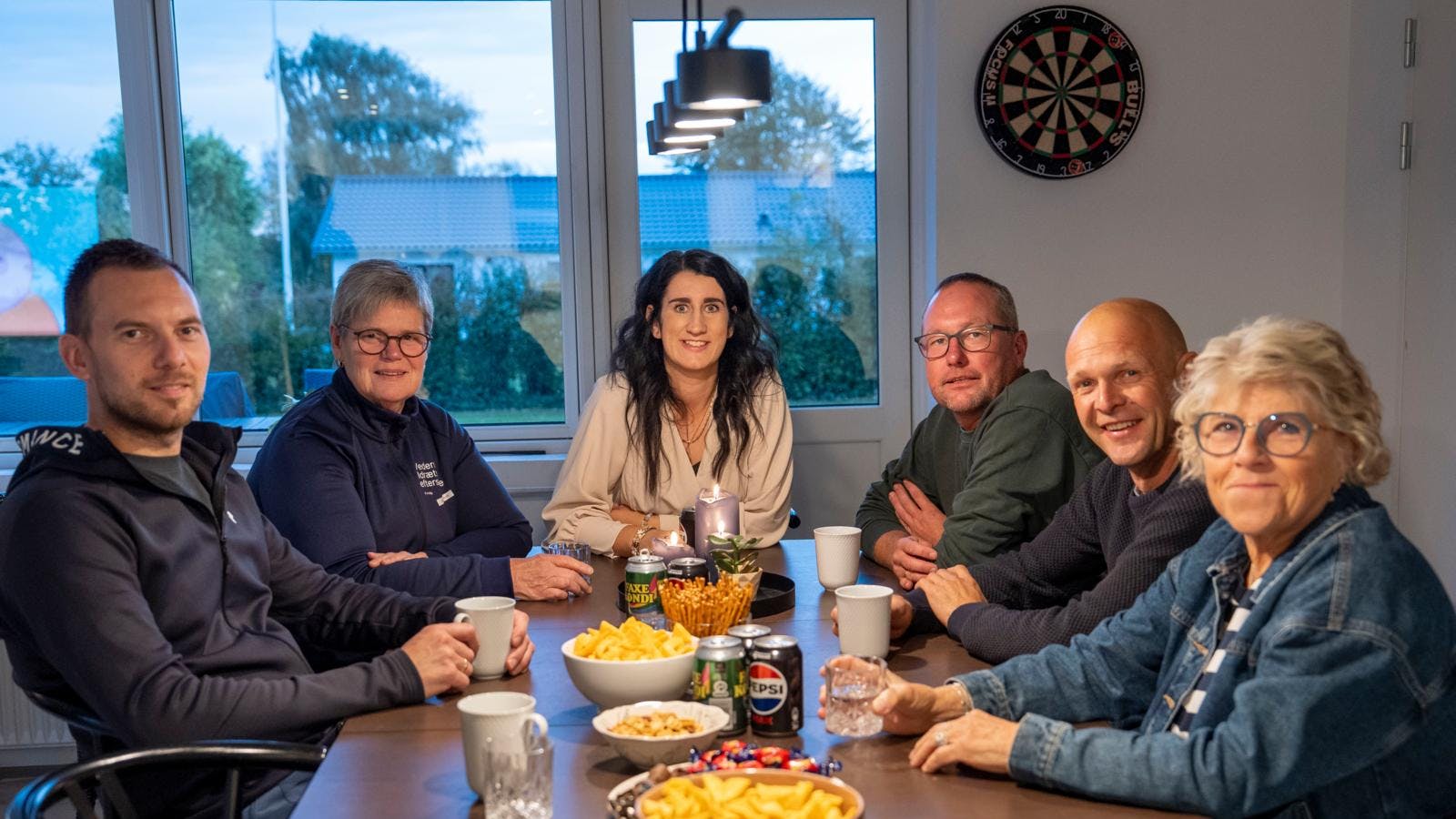 En gruppe mennesker, der sidder omkring et bord og smiler