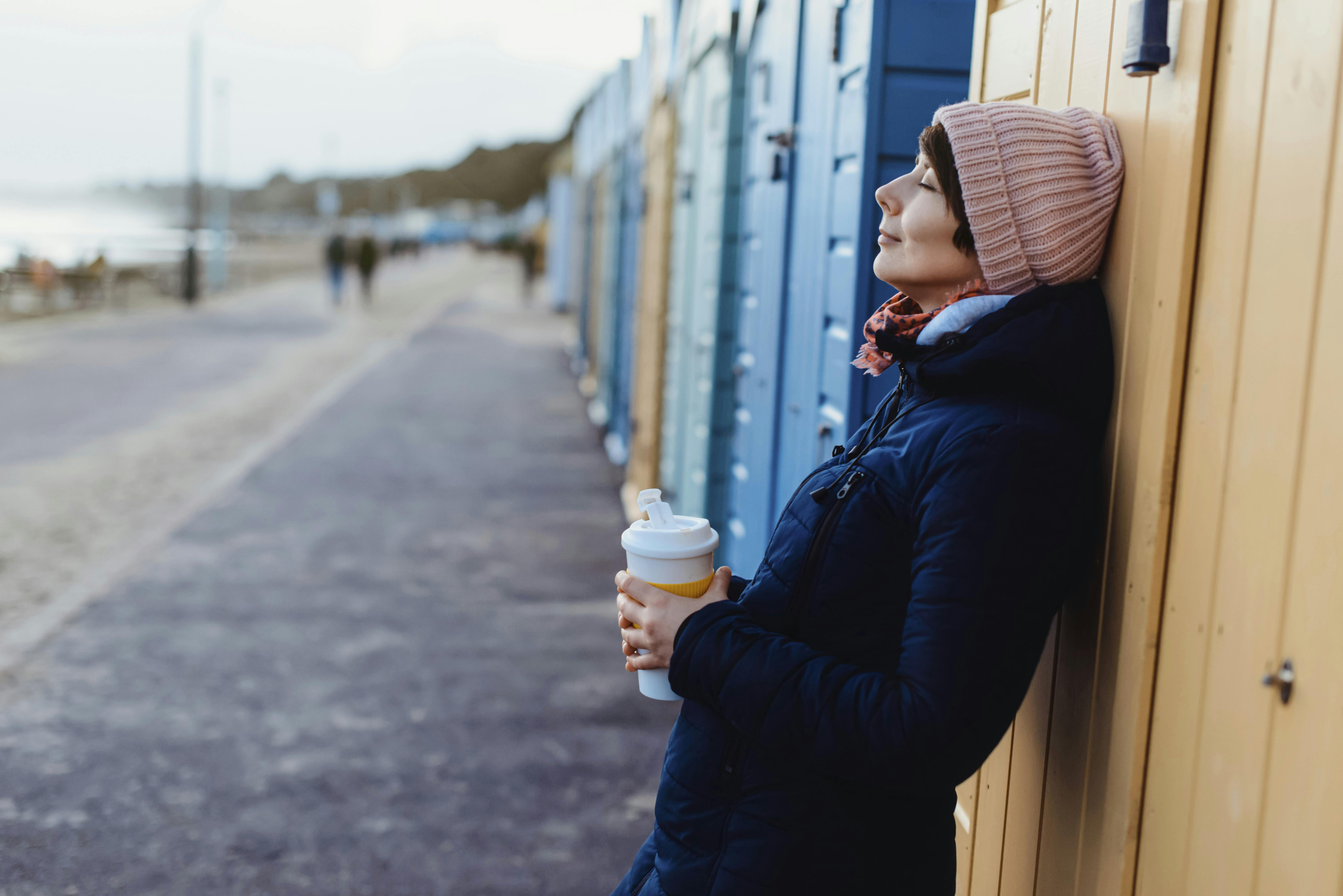 Smilende og afslappet kvinde med kaffekop i hånden