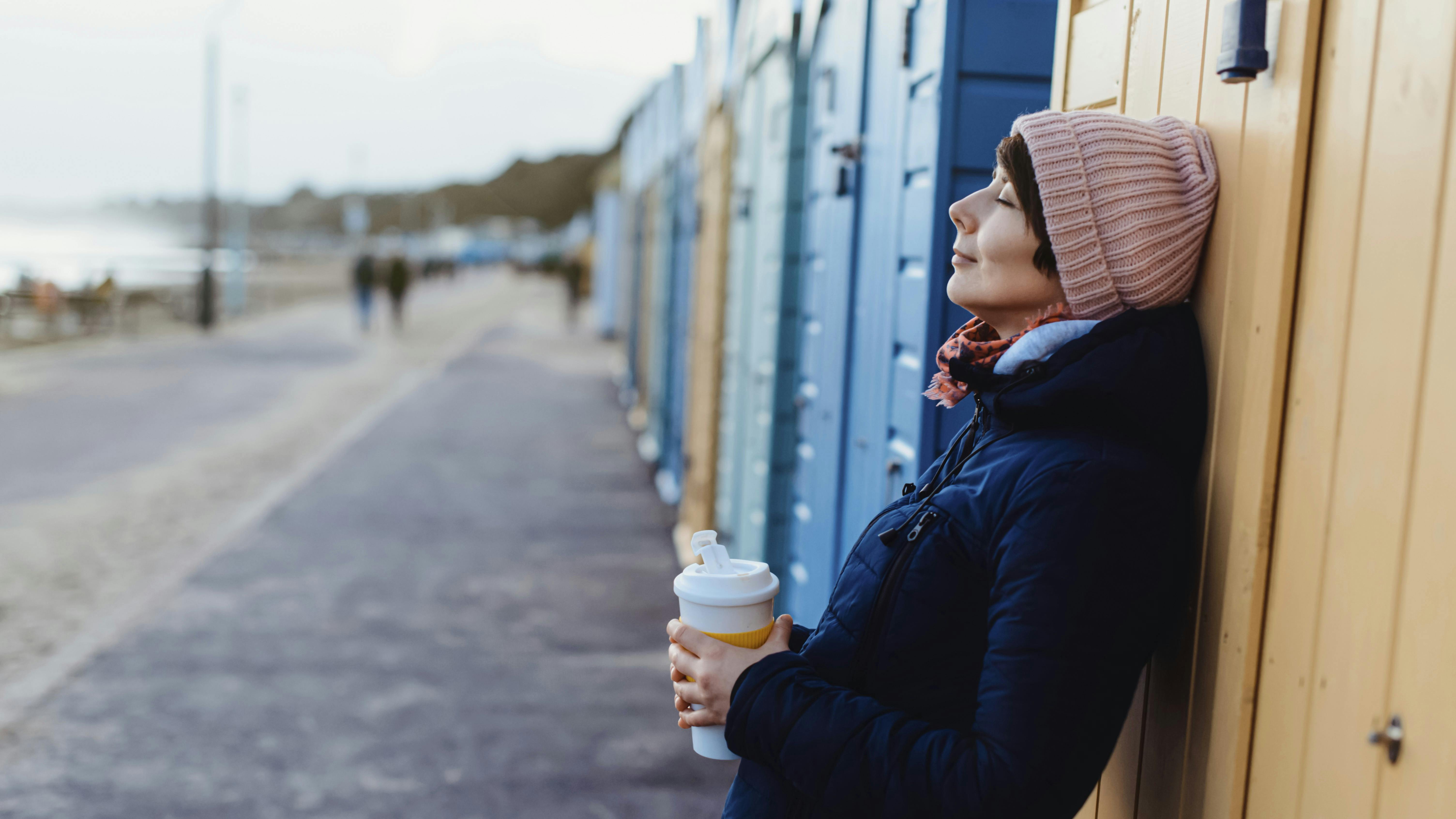 Smilende og afslappet kvinde med kaffekop i hånden