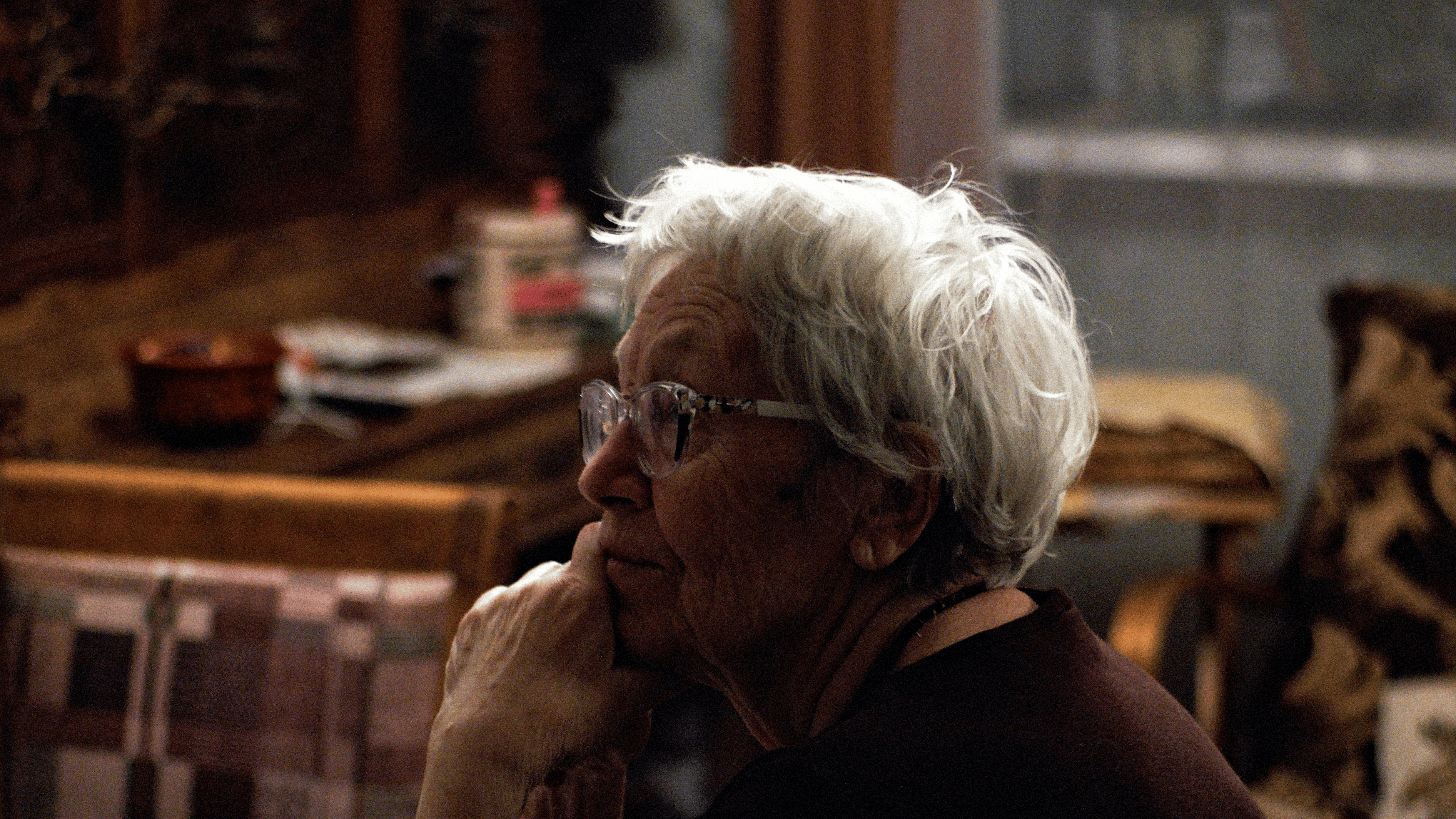 En ældre kvinde, der kigger til siden og ser eftertænksom ud.