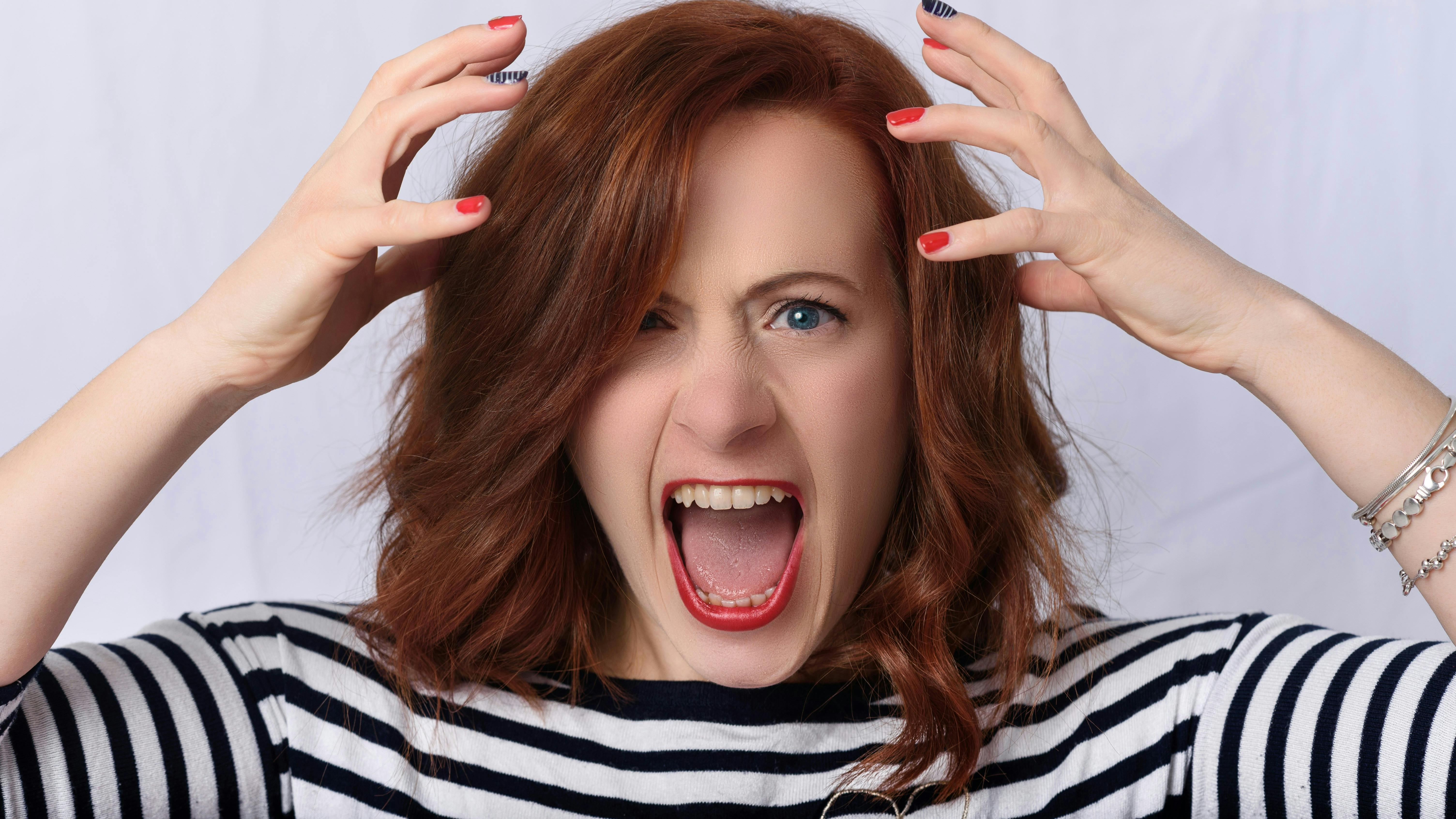 En frustreret kvinde, der tager sig til hovedet og skriger.