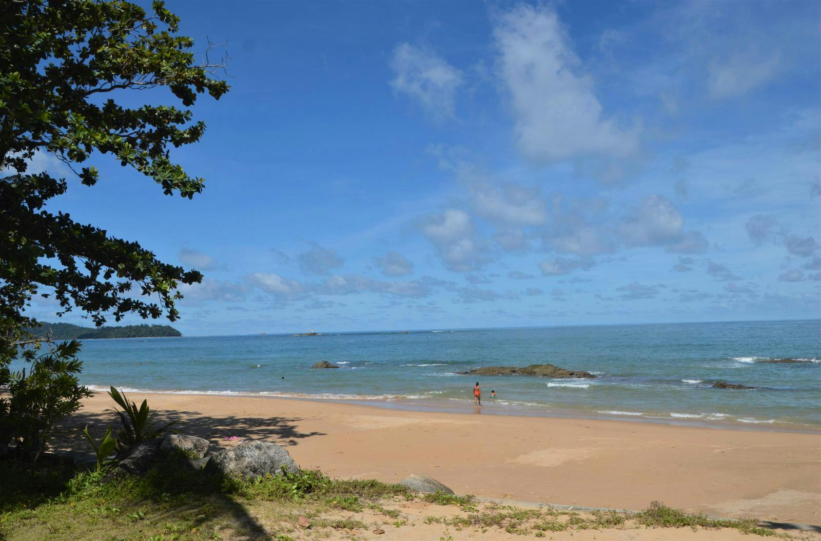 En thailandsk badestrand med aurblåt hav i baggrunden.