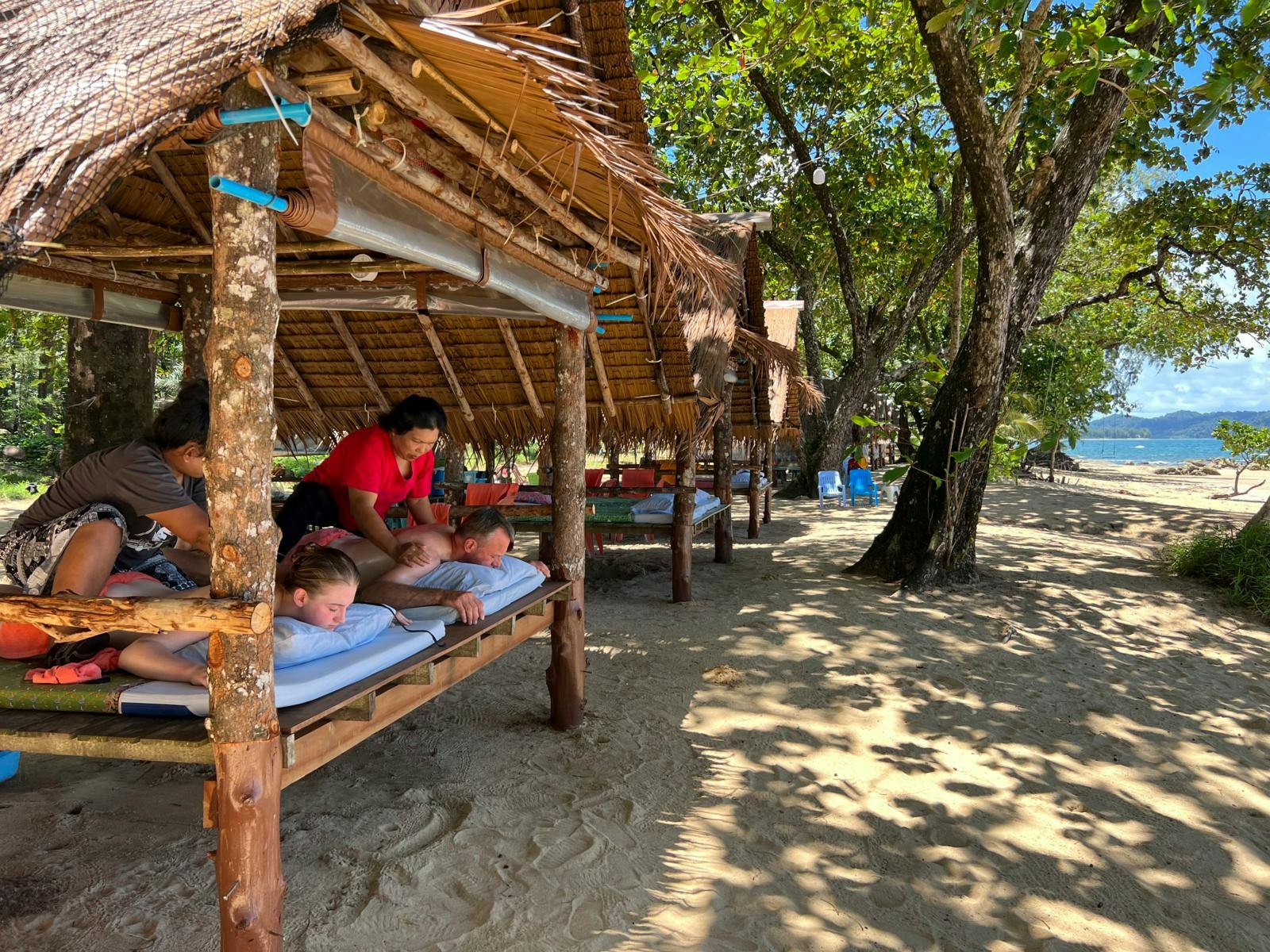 En åben bambushytte, hvor to kvinder får massage. 