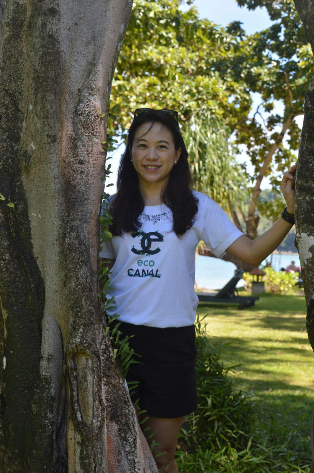 En ung, thailandsk kvinde står ved siden af et træ.