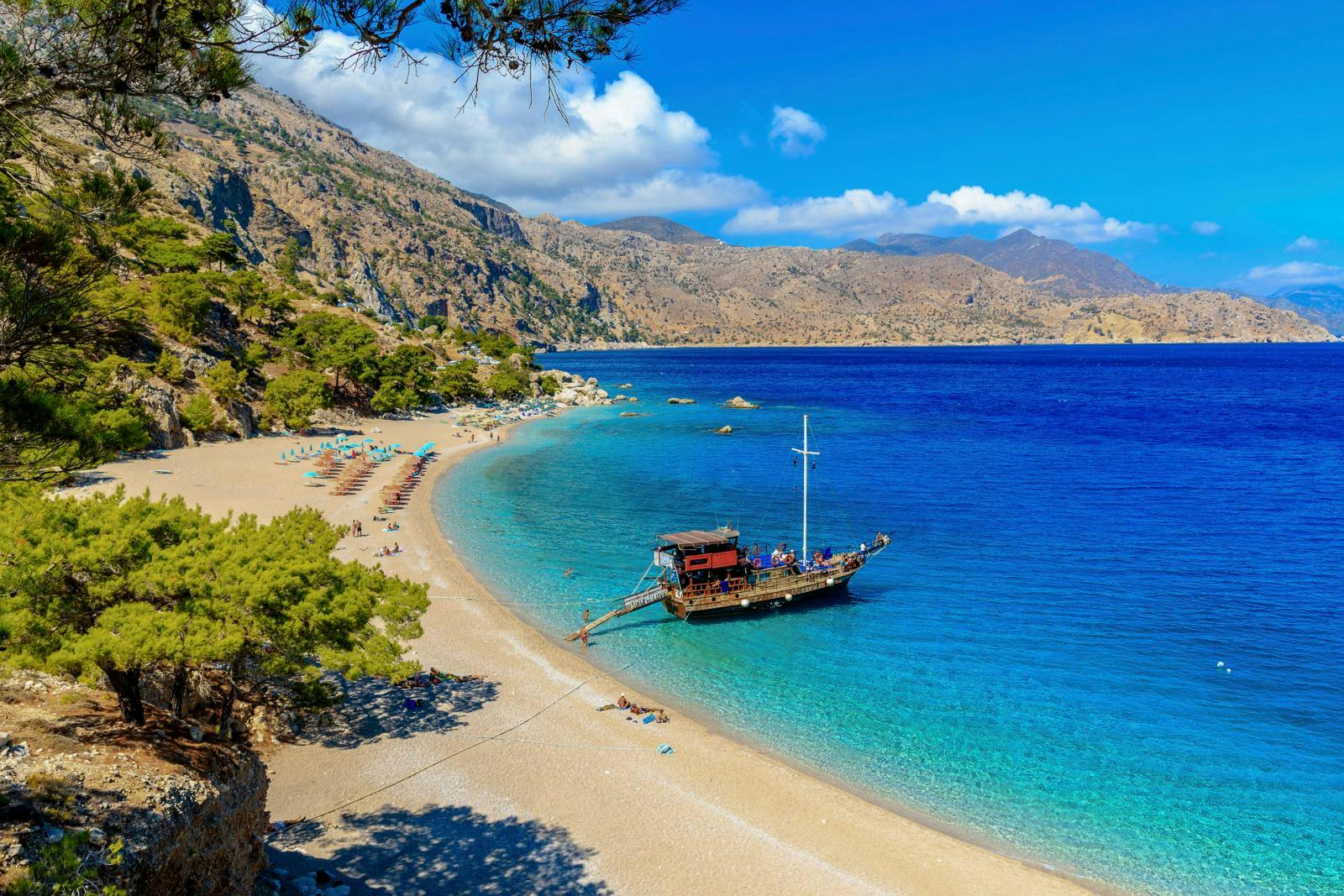 En sandstrand med dybt blåt hav og en enkelt båd
