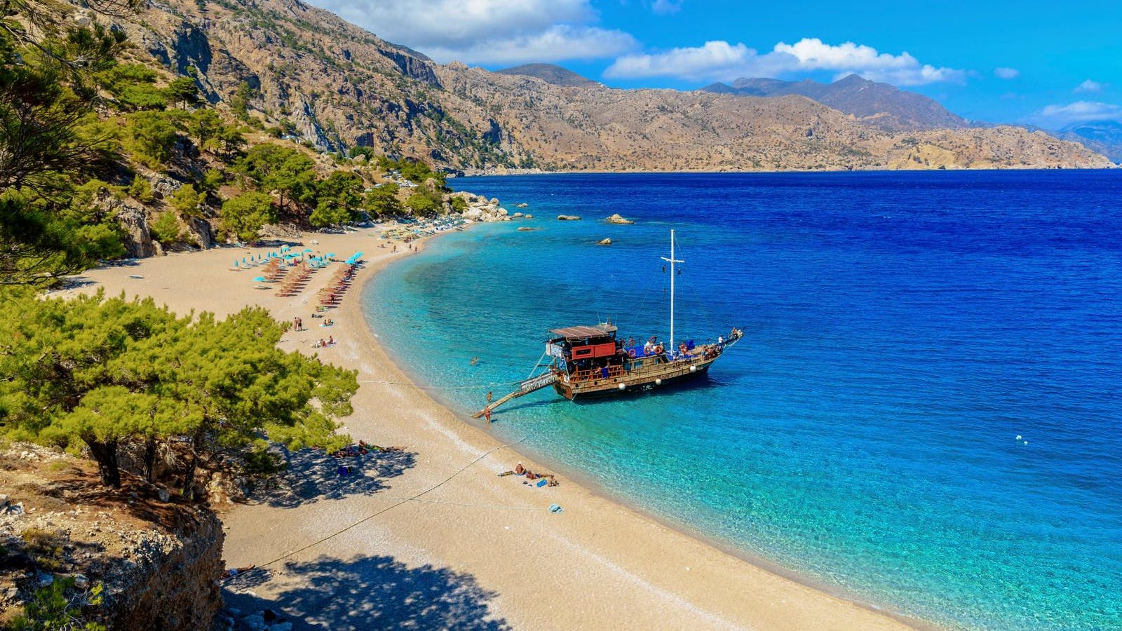 En sandstrand med dybt blåt hav og en enkelt båd