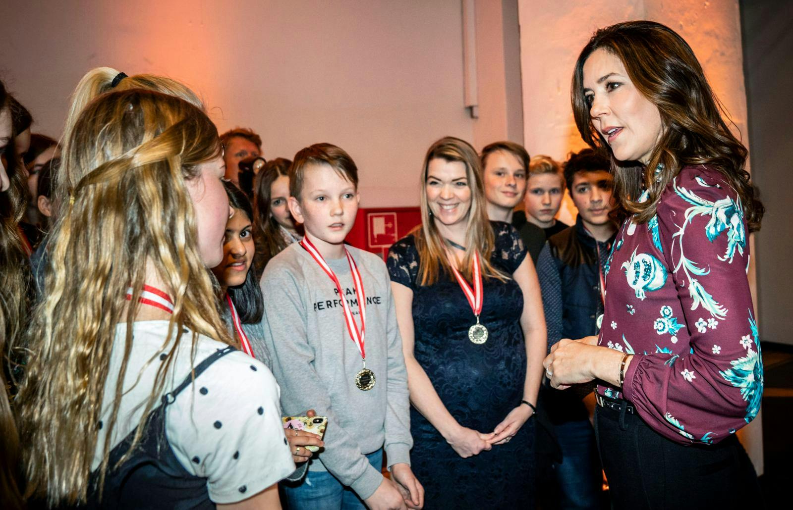 Kronprinsesse Mary omgivet af teenagebørn, som hun taler med.