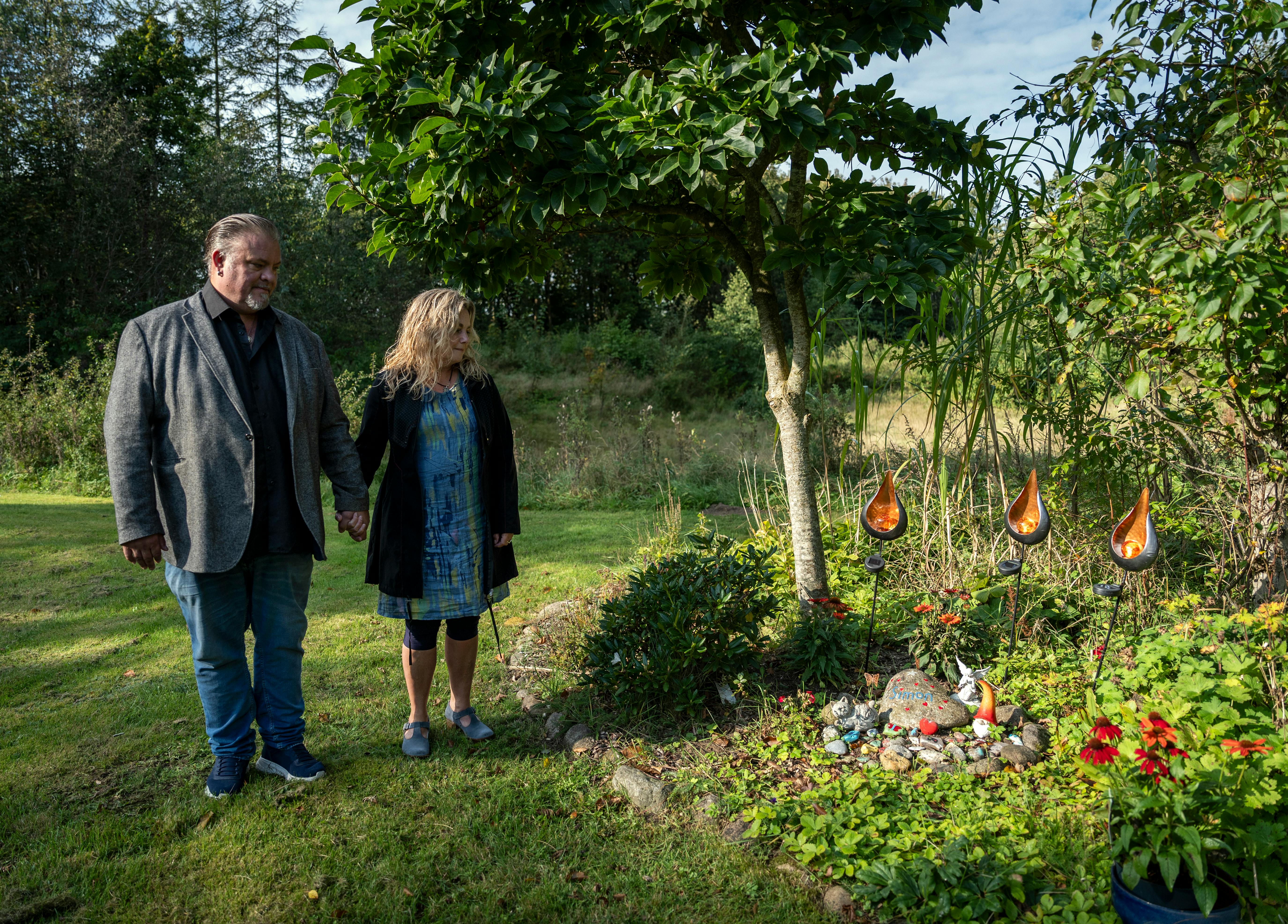 Christine Dueholm og Perry Stenbäck ved mindesmærket for deres søn Simon i haven, som både familiemedlemmer og Simons venner har leveret dybt personlige bidrag til.