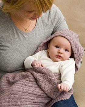 Baby sidder på skødet med tæppe om sig